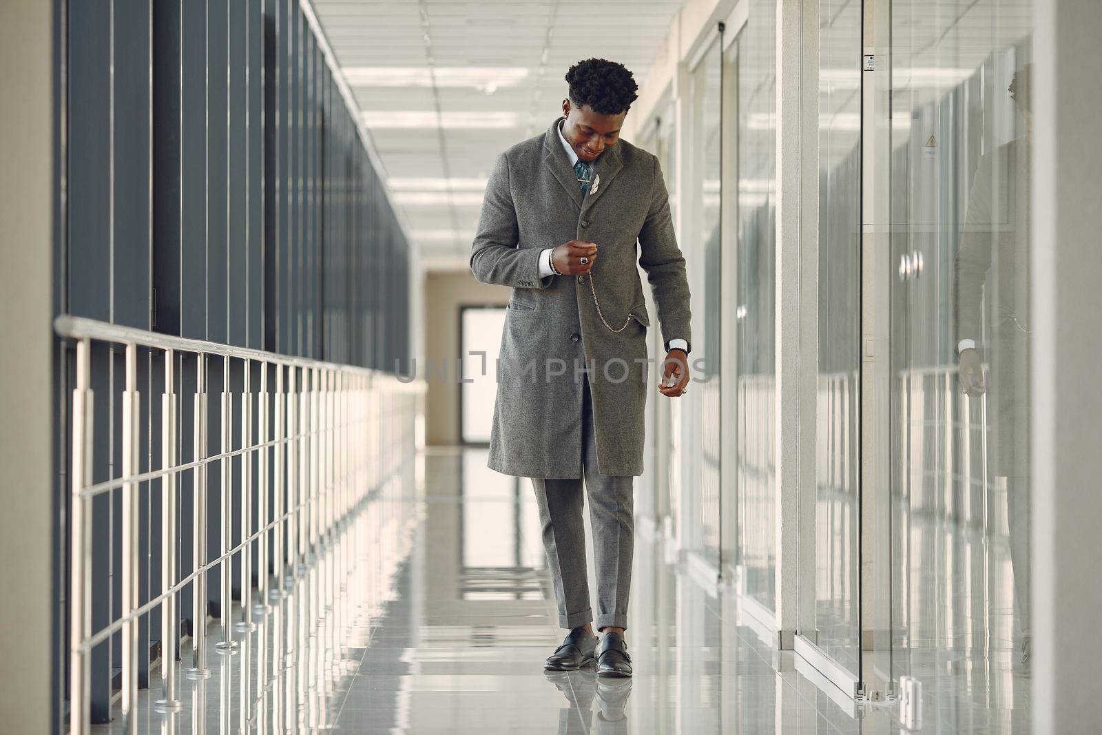 Black man in gray coat. Businessman working in a office. Guy at the lobby.