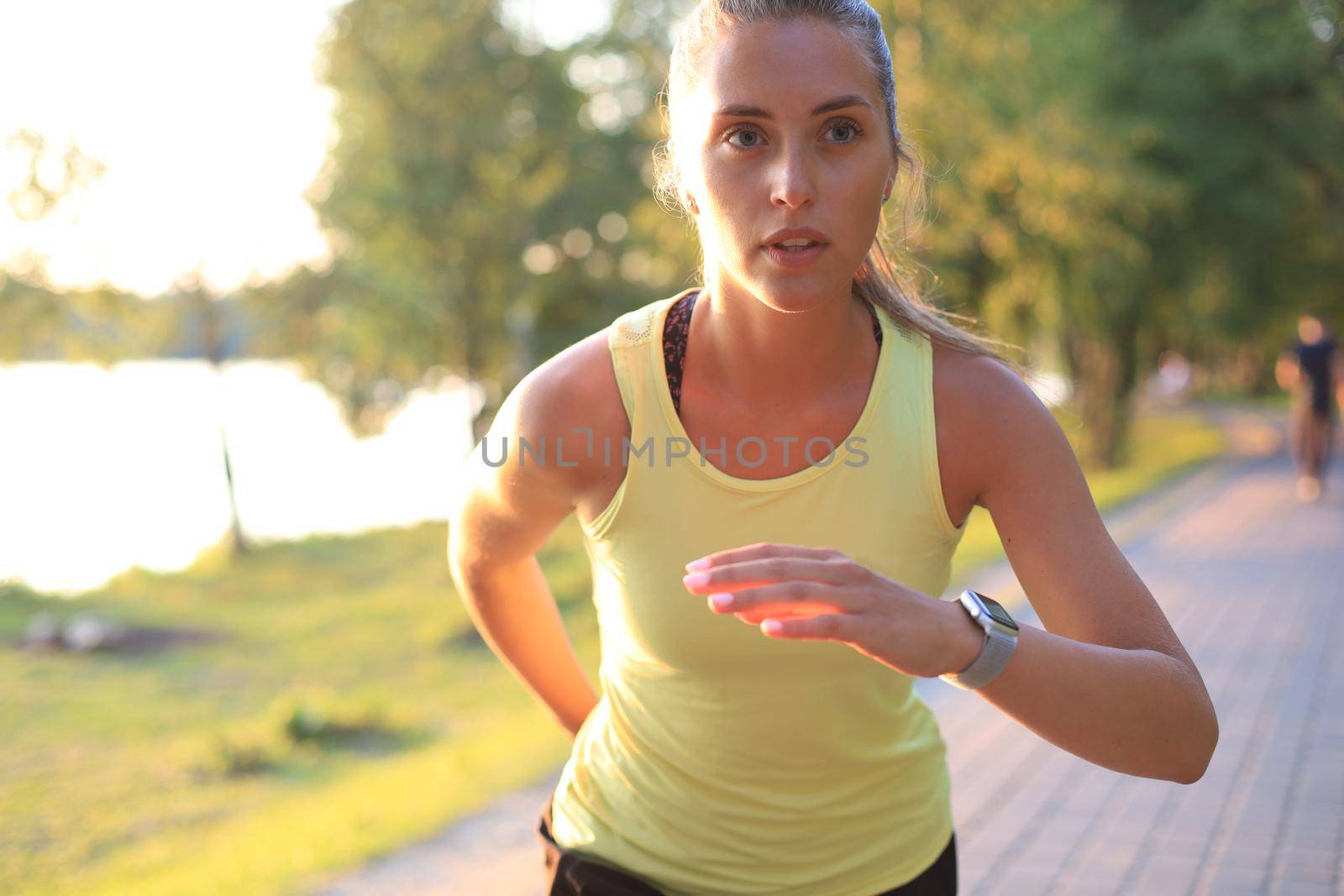 Young woman in sports clothing running while exercising outdoors. by tsyhun