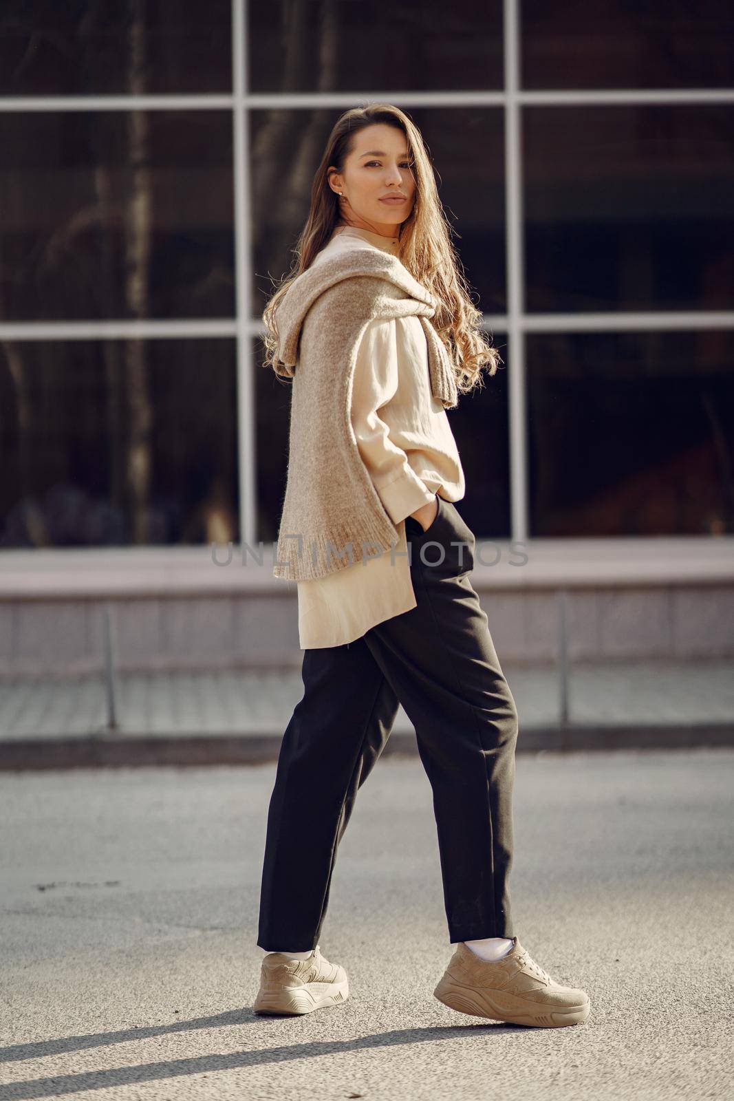 Woman in a brown shirt. Girl in a spring city. Lady by the building.