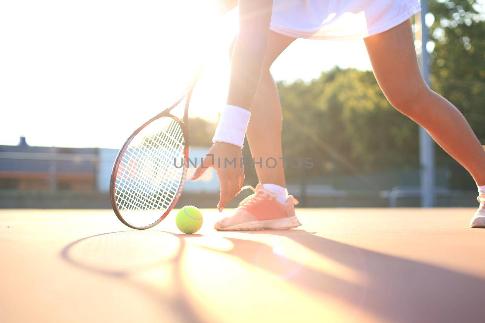 Tennis player raises a tennis ball from the clay court during the game. by tsyhun