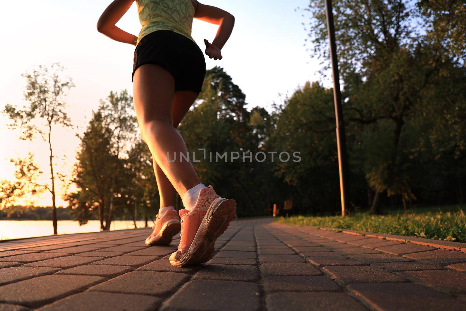 Runner feet running on road closeup on shoe, outdoor at sunset or sunrise. by tsyhun