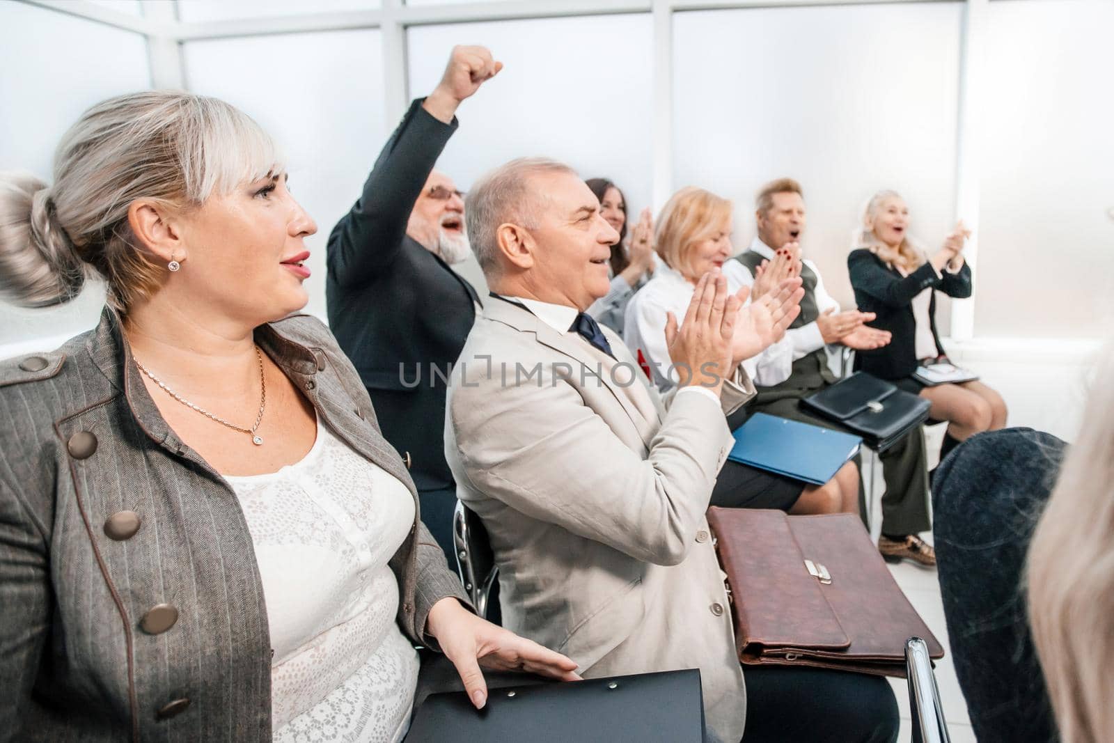 side view. smiling business seminar listeners applauding together. business and education