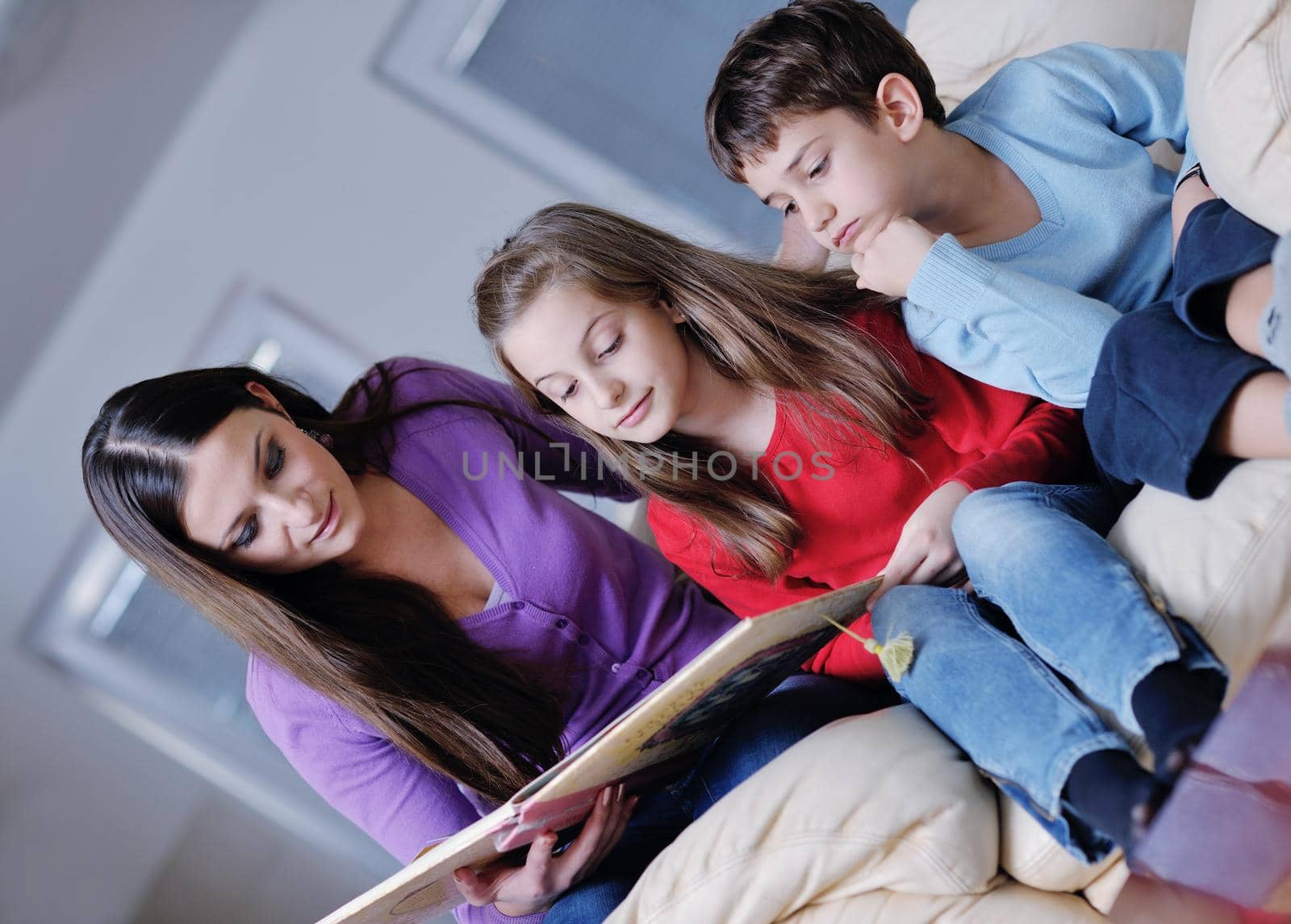 young mother read book to their kids at modern new home living room indoor