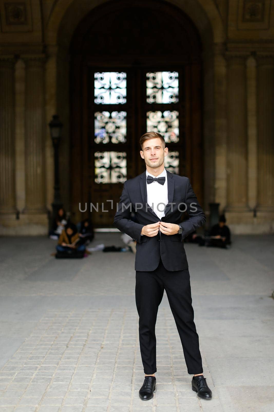 Young european guy standing and posing, wearing black suit and bow tie. by sisterspro