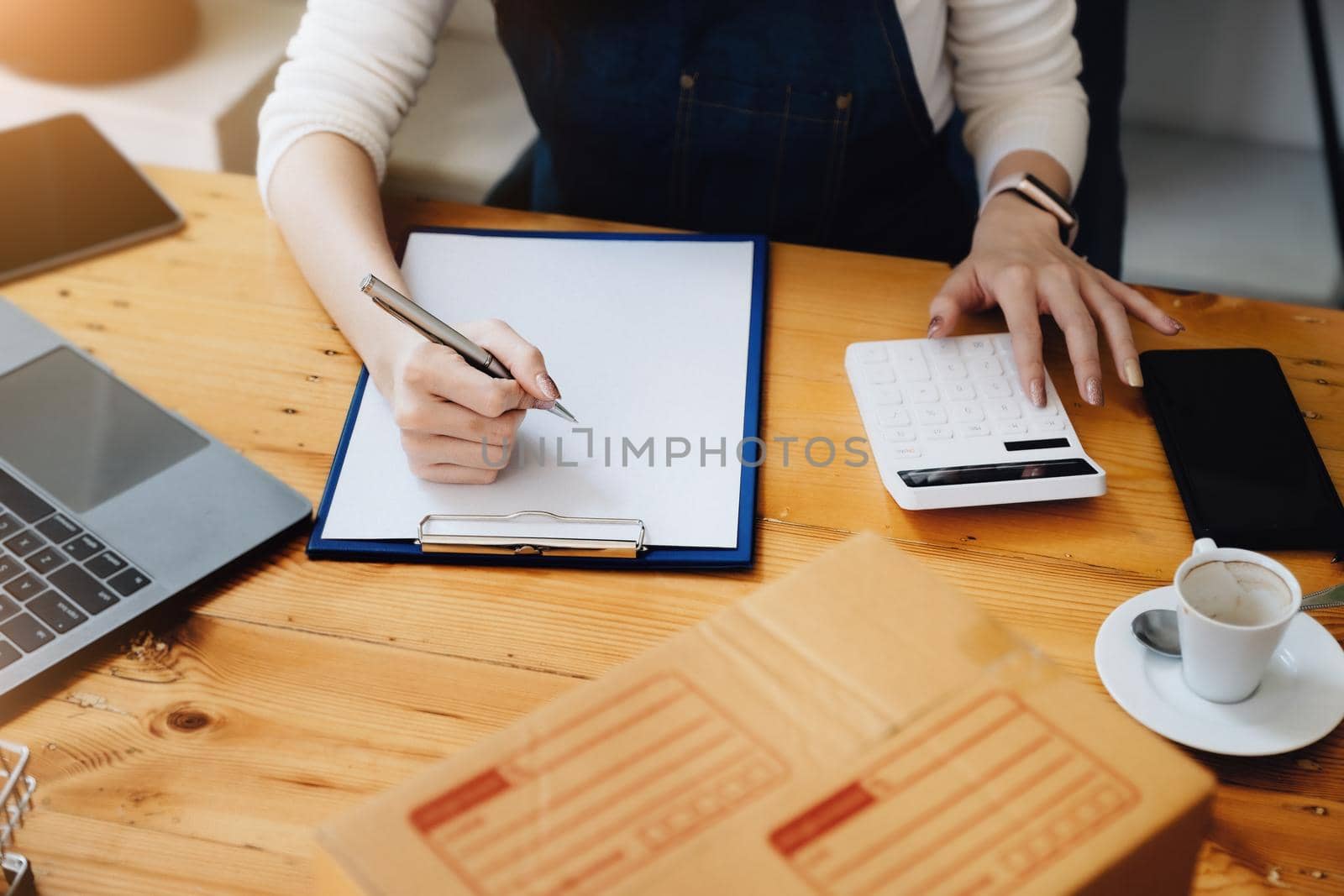 Entrepreneur owner using pen point note laptop and calculator checking online purchase shopping order to preparing pack product box. Packing goods for delivery to customer