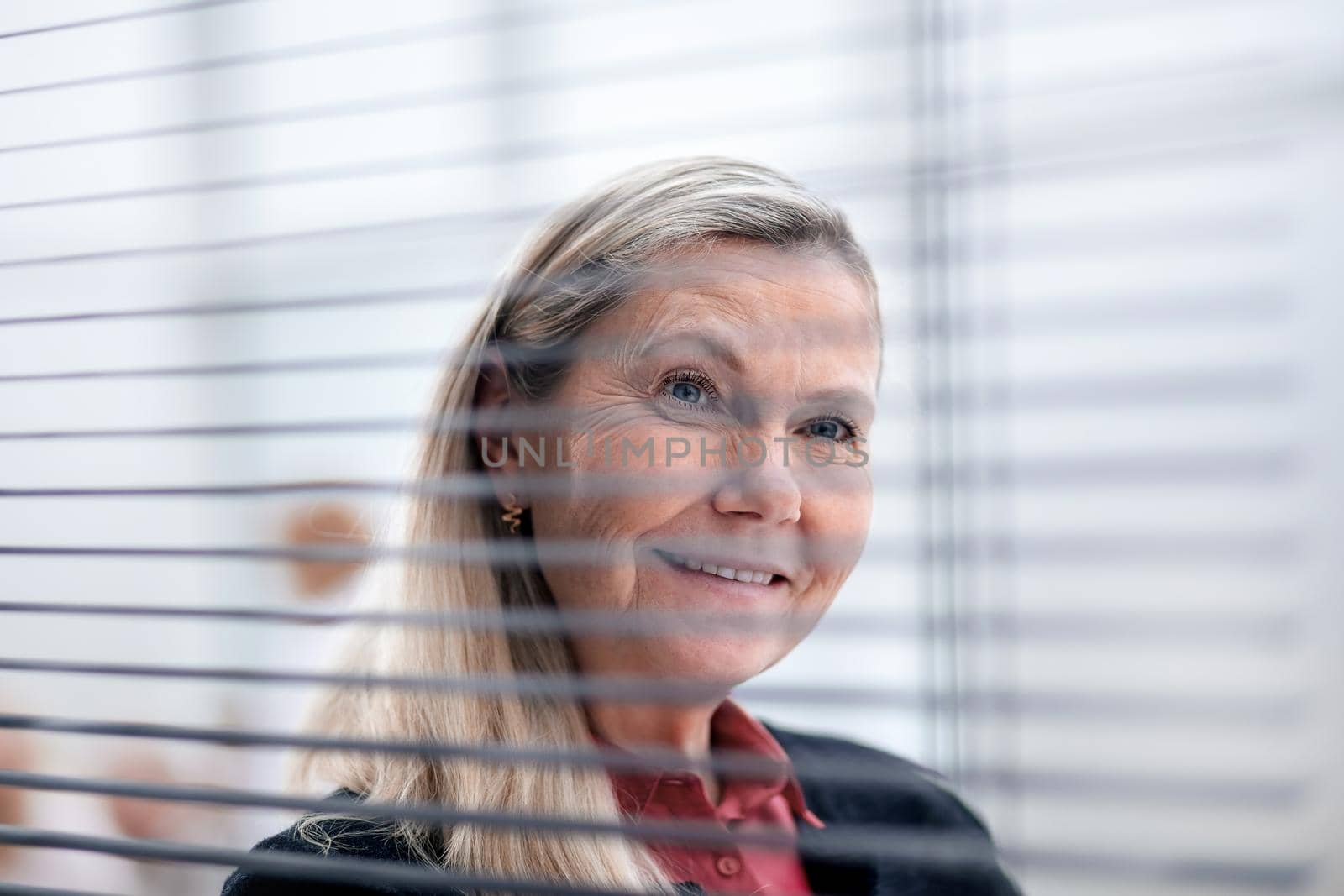 close up. senior business woman looking through office blinds