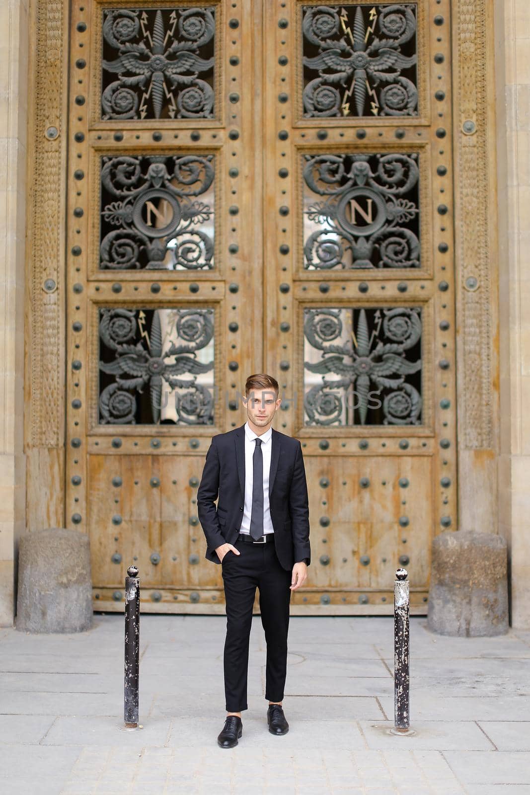 Handsome young man standing near wooden door. by sisterspro