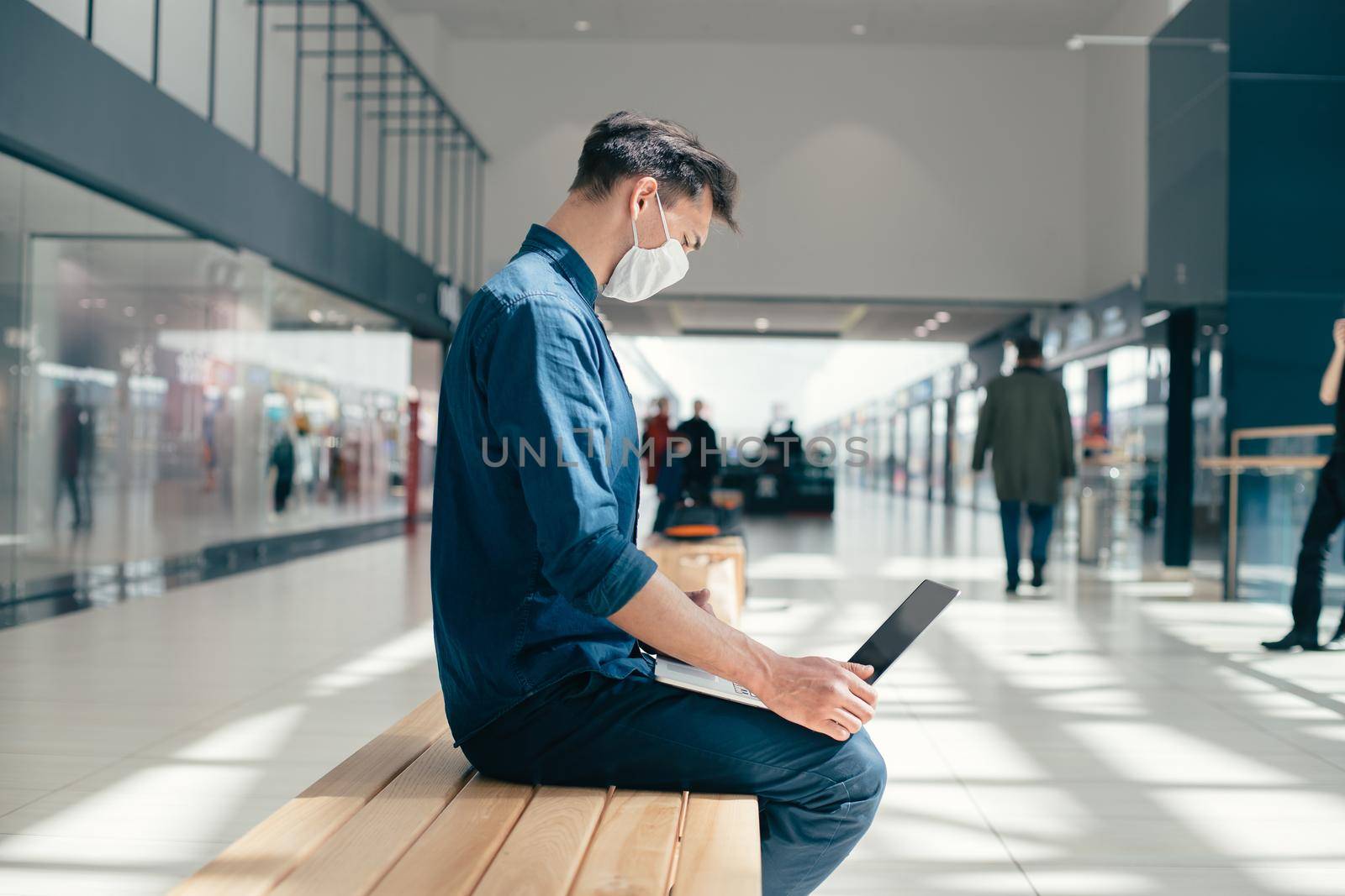 man in a protective mask works on a laptop near a city building. pandemic in the city