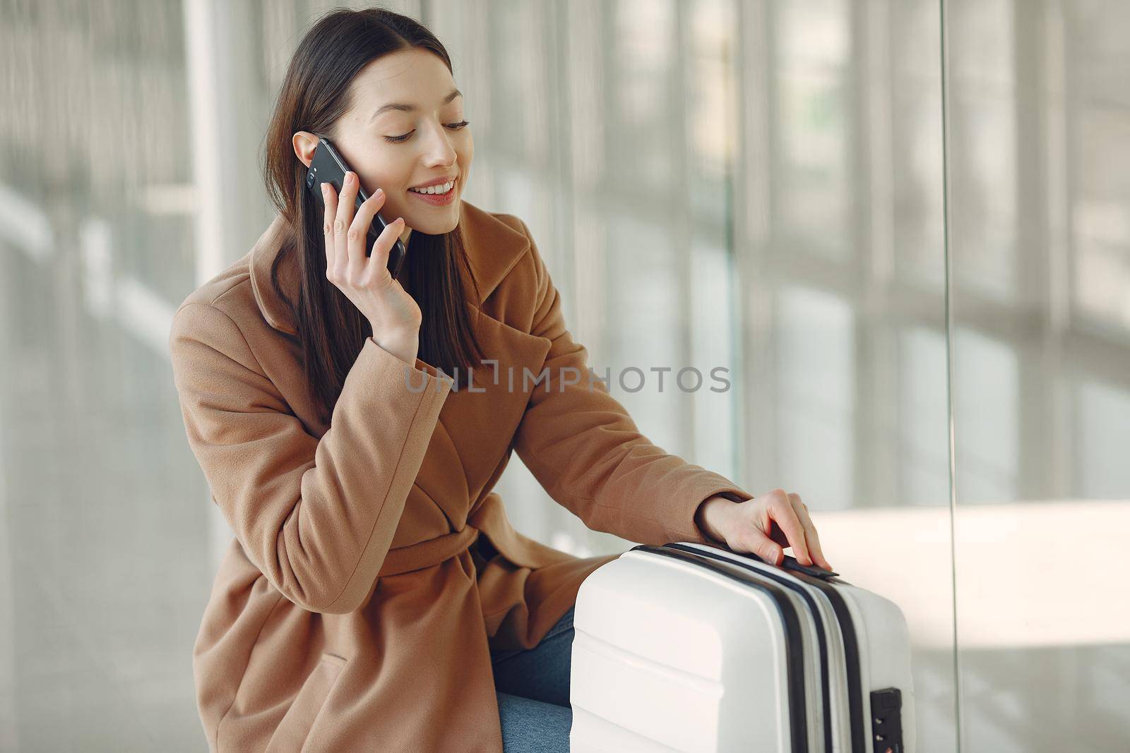 Woman at the airport. Girl with suitcase. Lady in a brown coat.