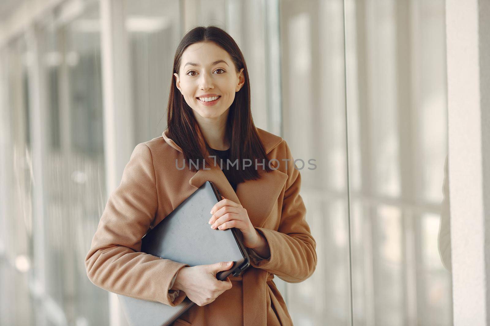 Girl in the office. Woman in a brown coat. Lady with a laptop.