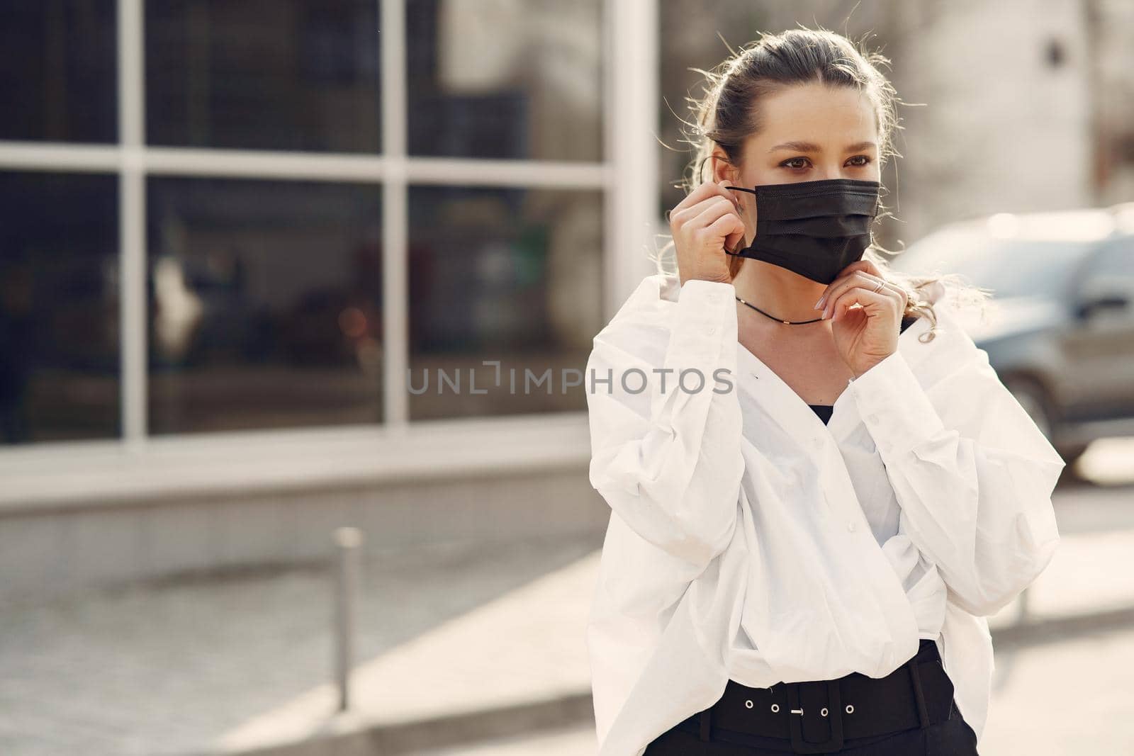 Woman in the city. Person in a mask. Coronavirus theme. Woman in a white shirt.