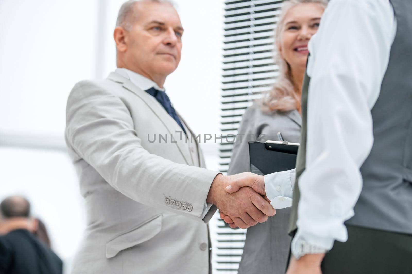 close up. serious business man shaking hands with his colleague by SmartPhotoLab