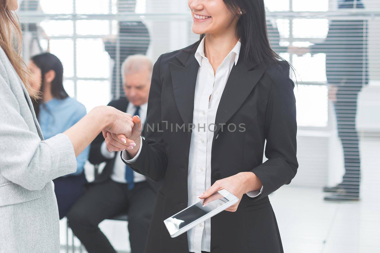 two business women shaking hands with each other. by SmartPhotoLab