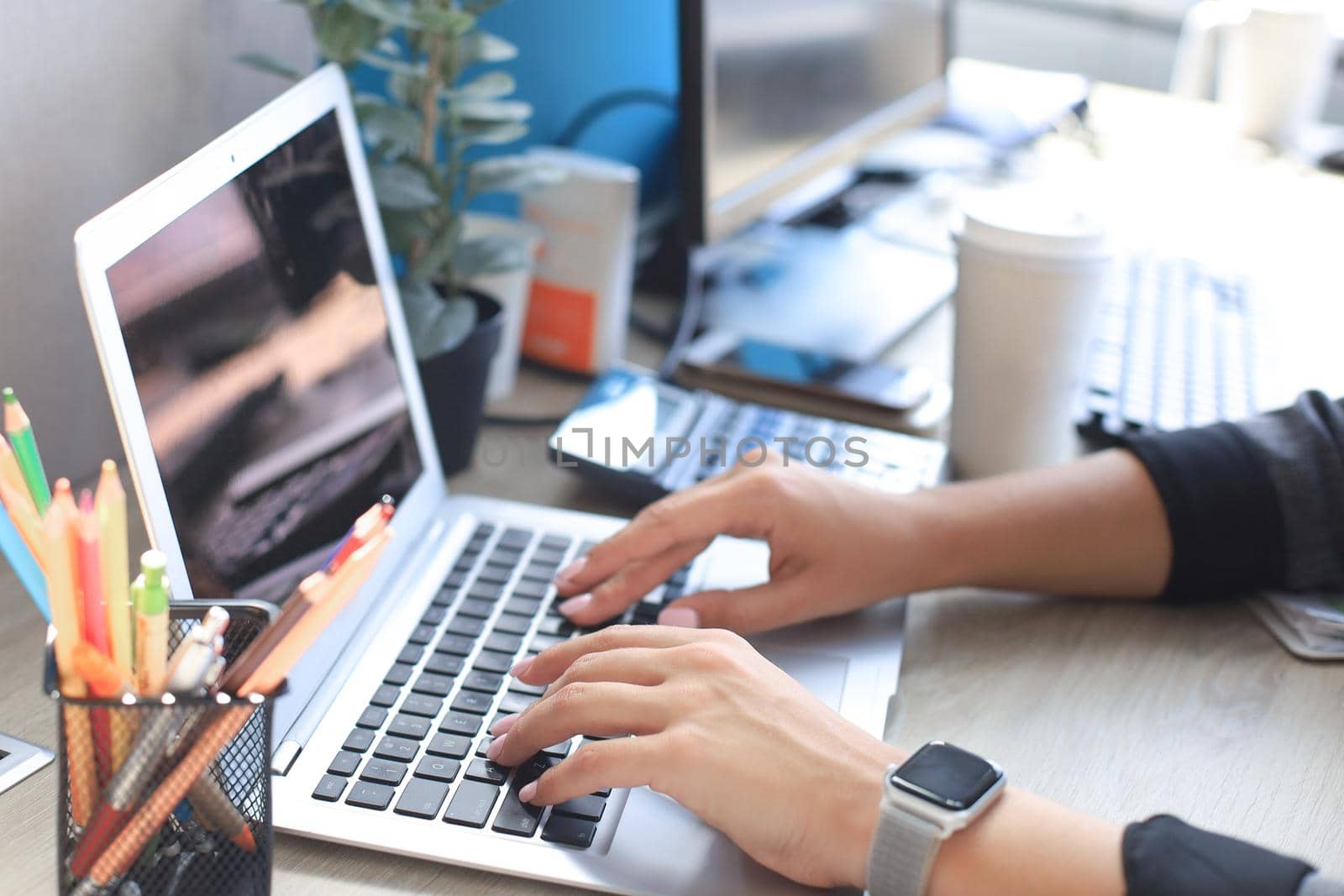 Woman hands pressing keys on a laptop keyboard in office