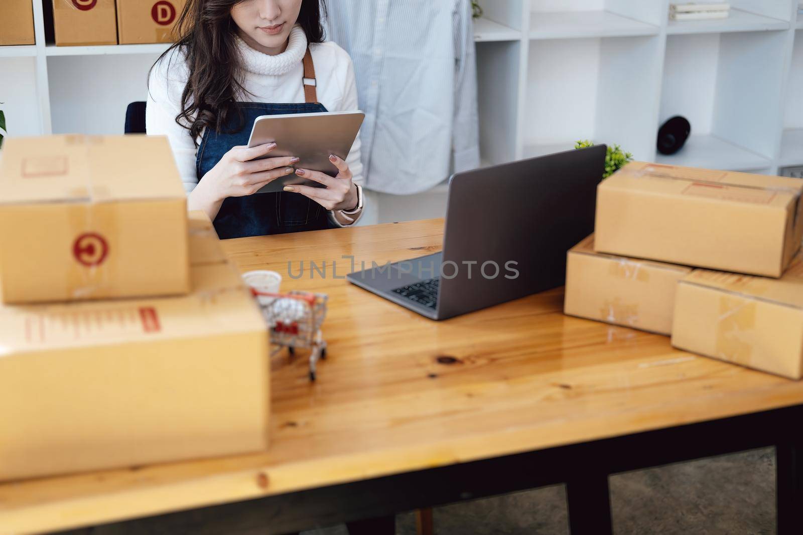 Work from home. happy women selling products online Start a small business owner by using tablet and laptop computer to calculate prices and prepare for postage. by Manastrong