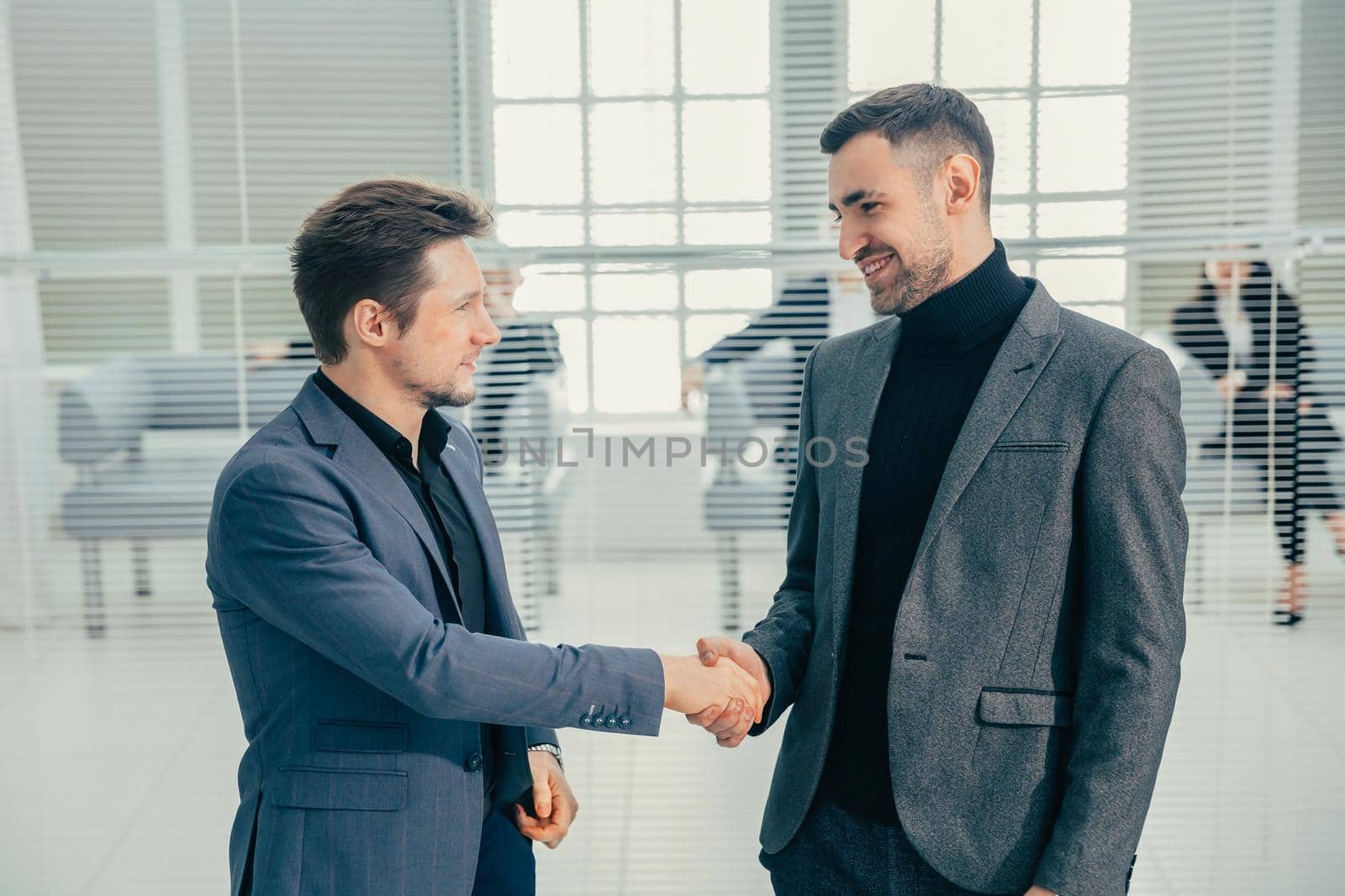 business people shaking hands standing in the office lobby. business concept.