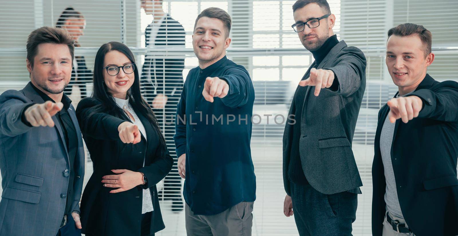 close up. group of smiling employees pointing at you.