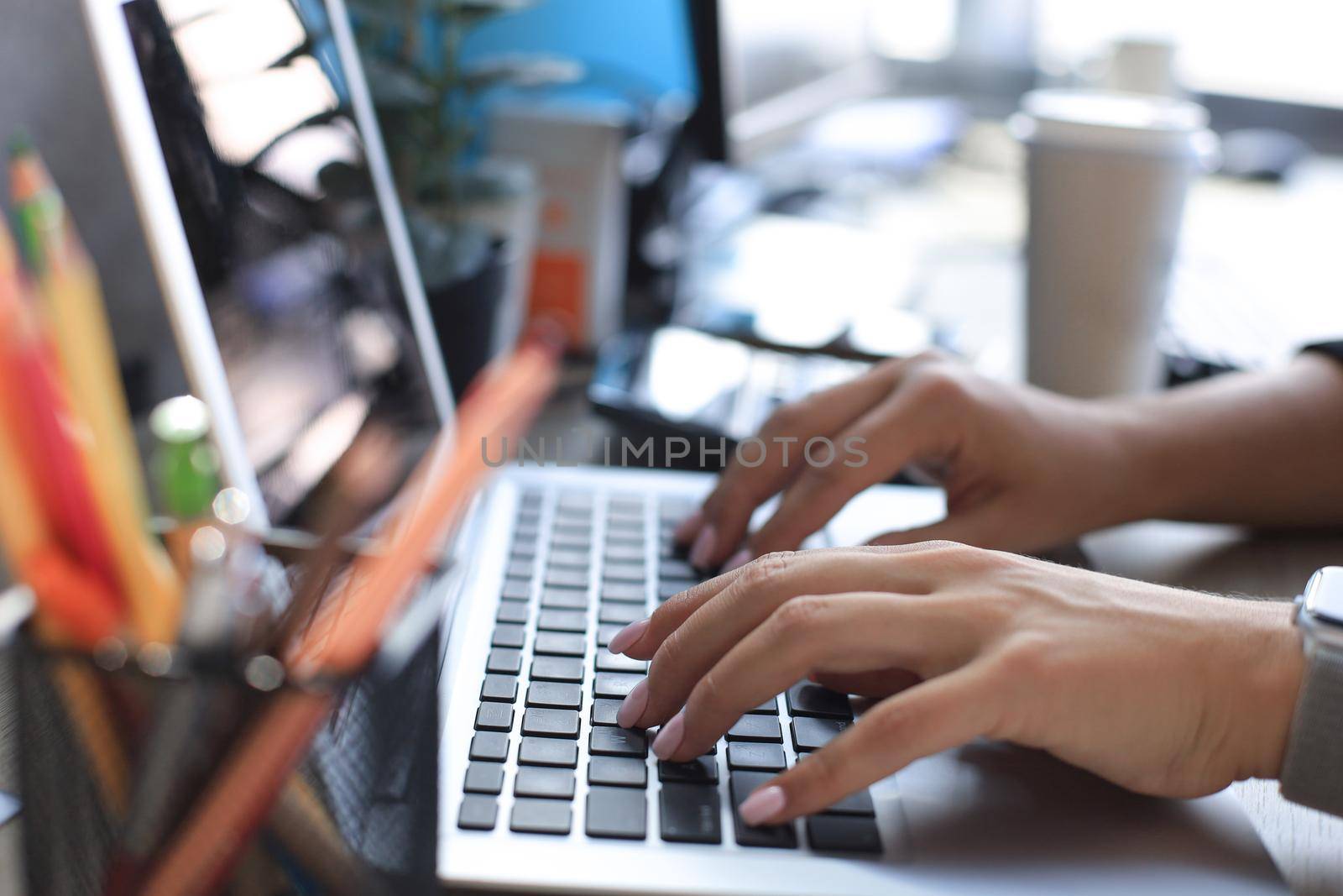Close up of female hands busy typing on laptop in modern office. by tsyhun