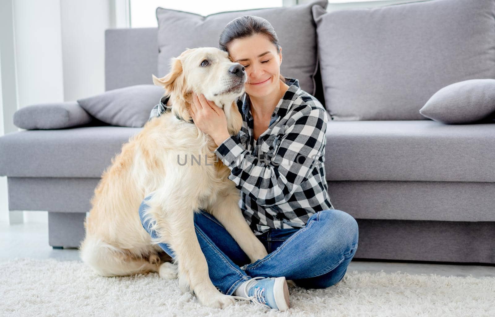 Beautiful woman cuddling lovely dog in light room