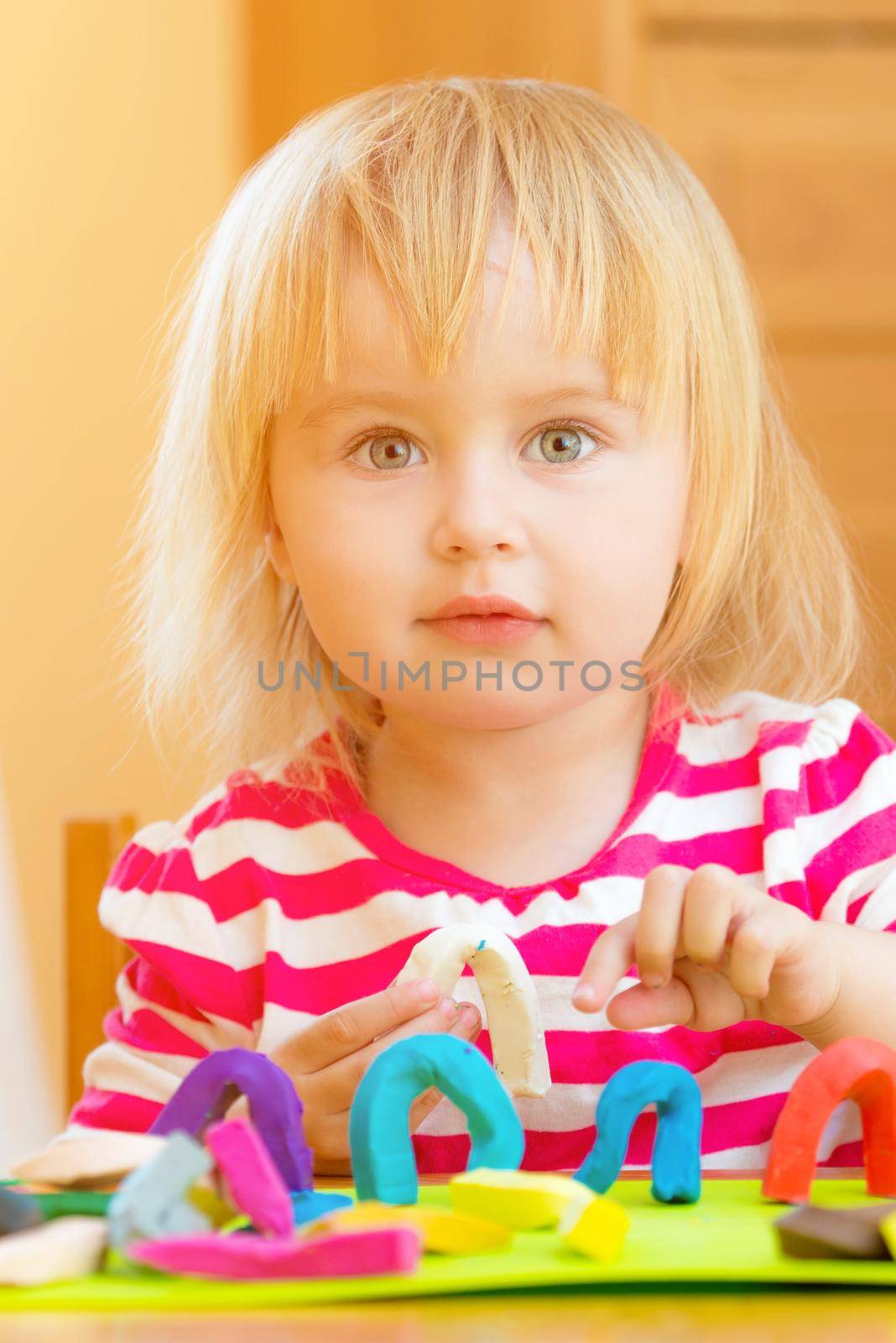 Little girl playing with plasticine at home