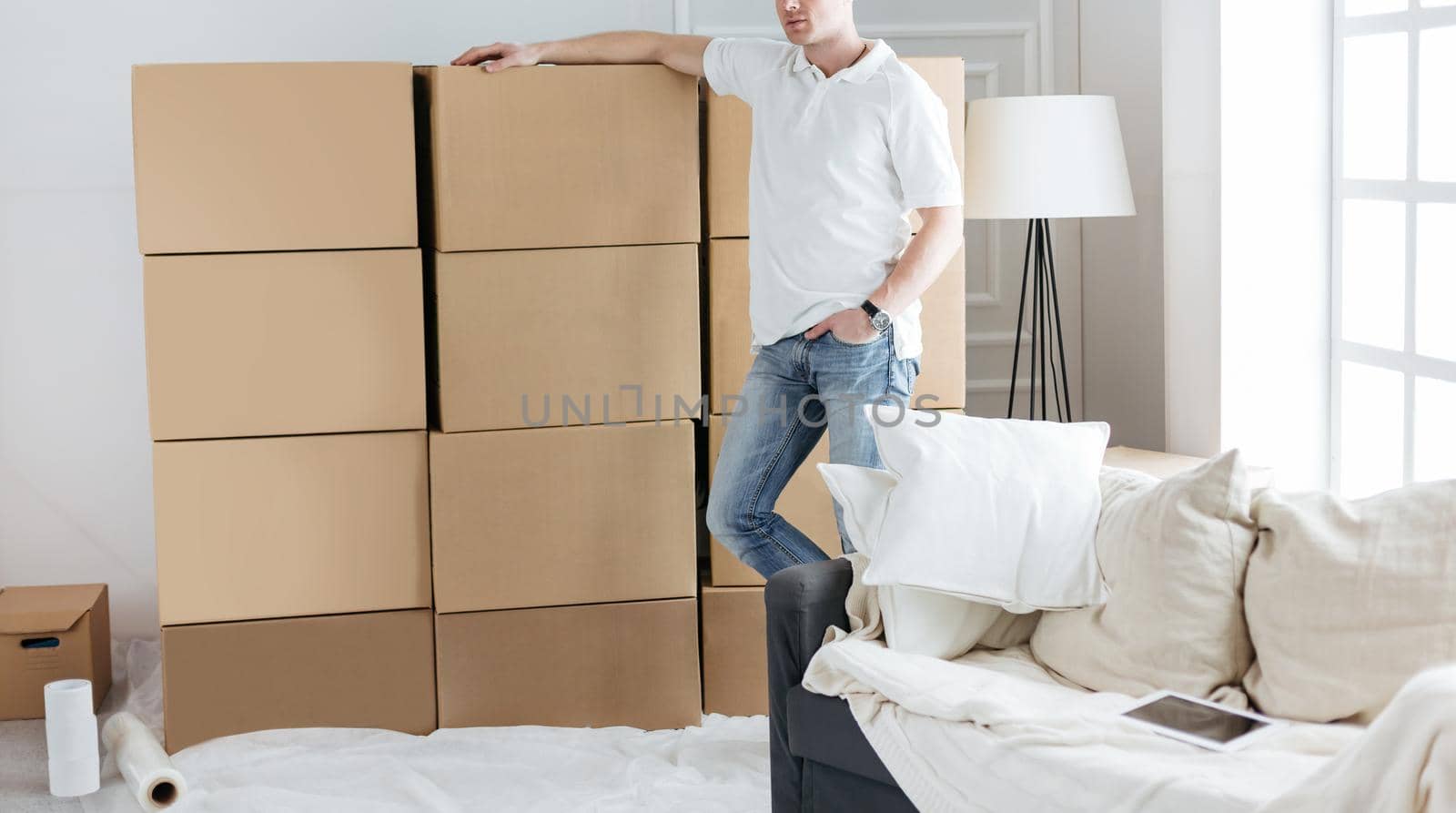 young man standing near boxes in his new apartment. photo with copy-space