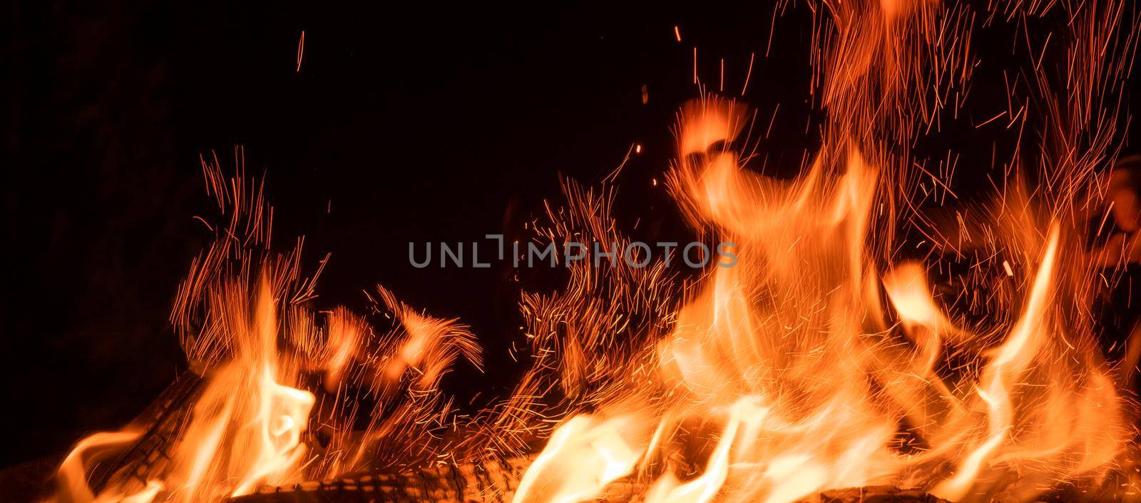 Beautiful flame of bonfire with sparks with dark night sky background. Fire tonques isolated on black background