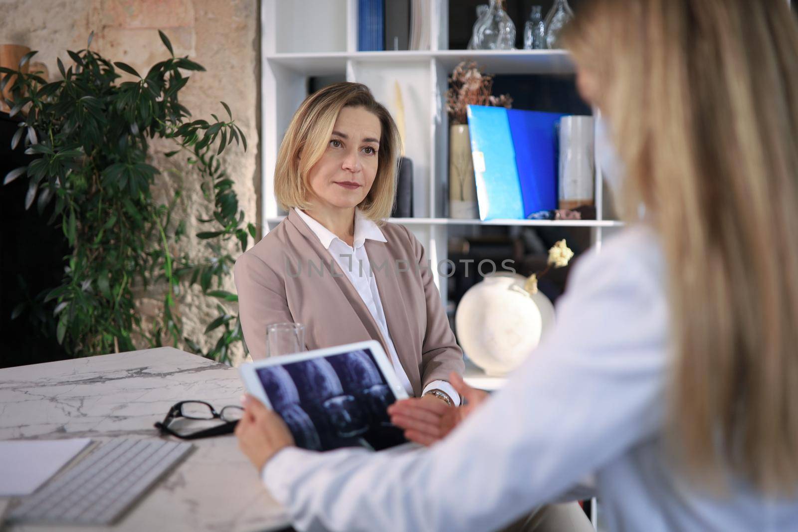 Middle aged female doctor therapist in consultation with patient in office