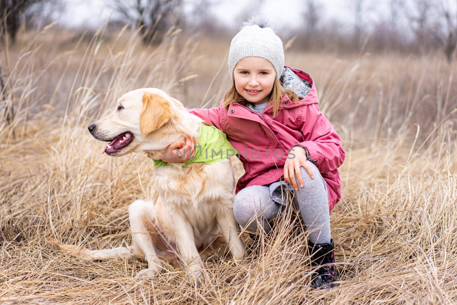 Little girl with cute dog in high dry grass