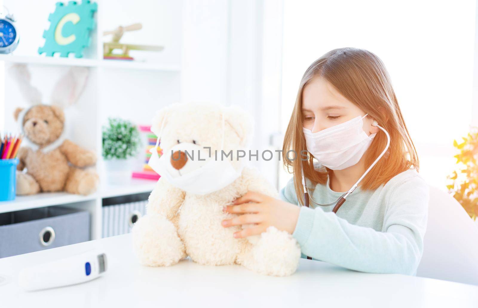 Cute little girl playing with teddy bear in light room