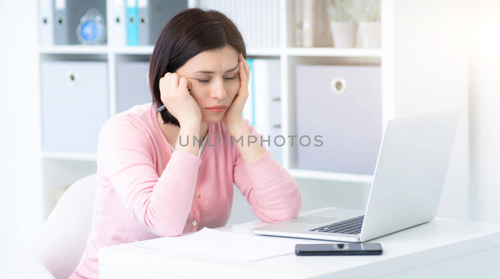 Tired woman at workplace in light office