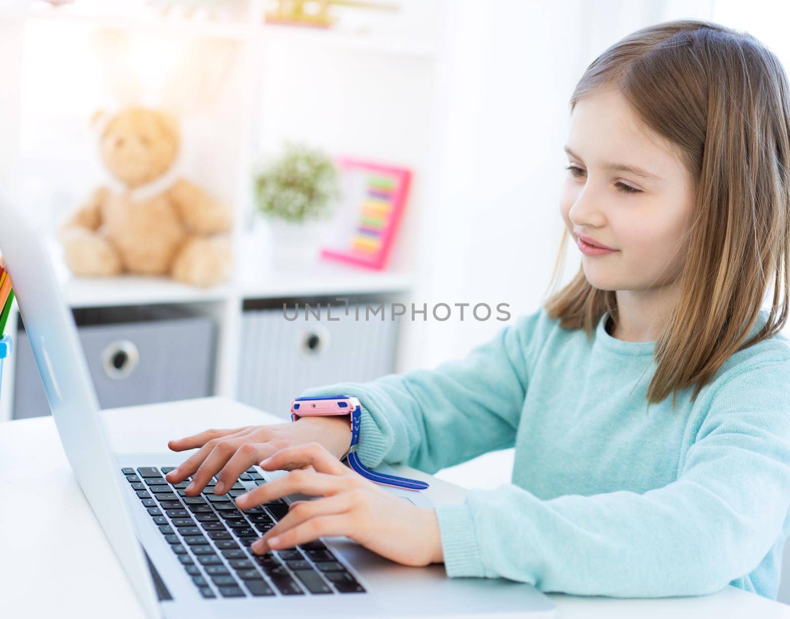 Cute little girl using computer in light room