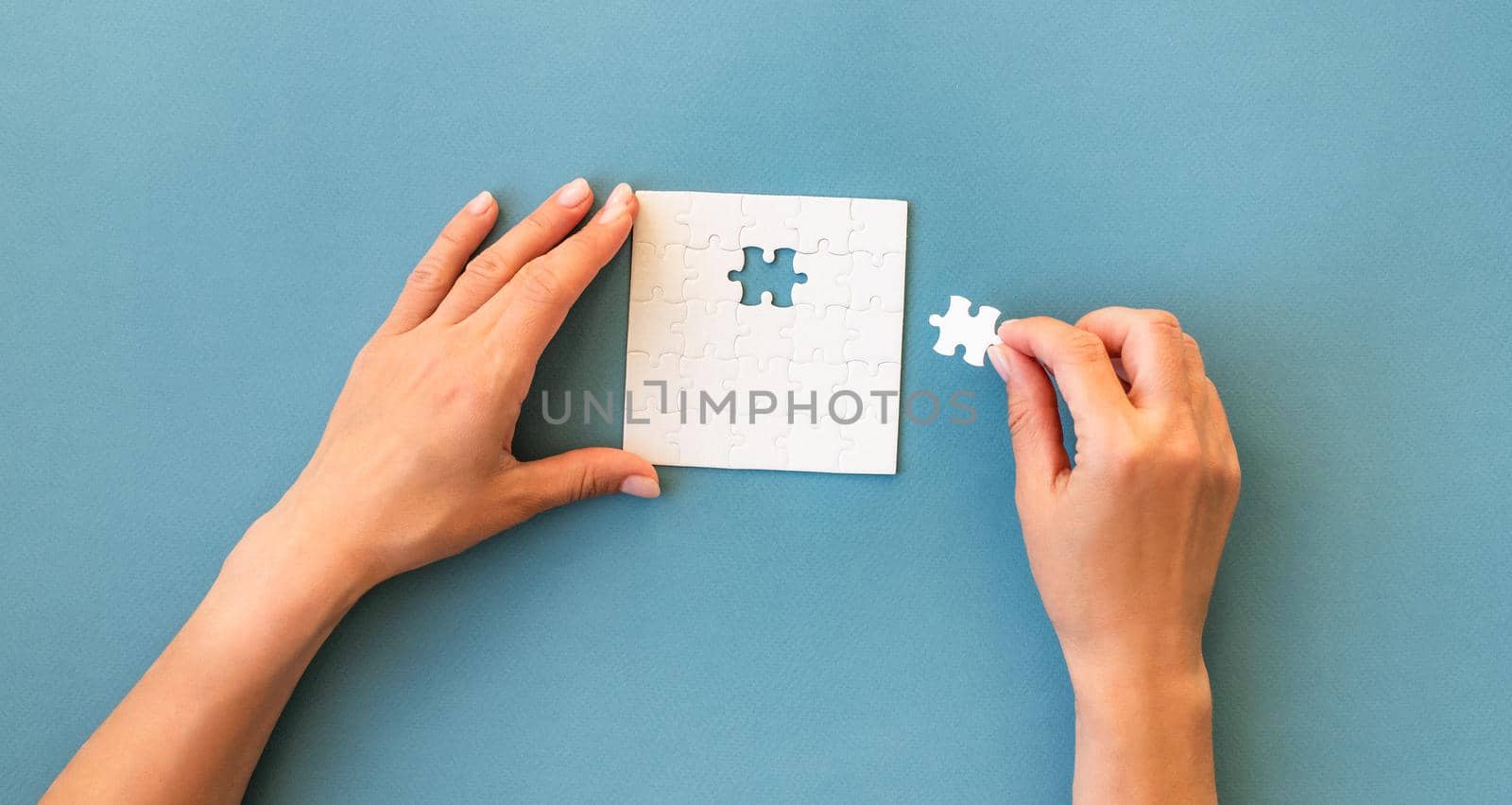 Hands with Small white square puzzle on a blue background