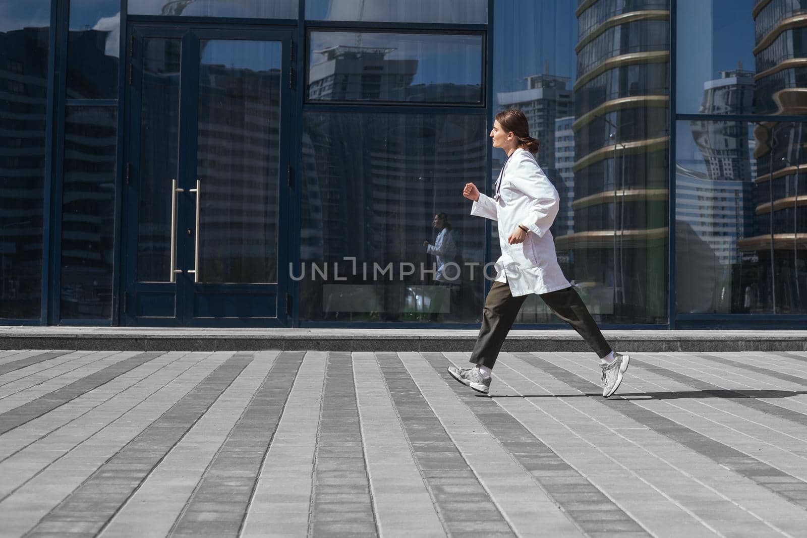 woman doctor runs down a city street. photo with a copy-space.