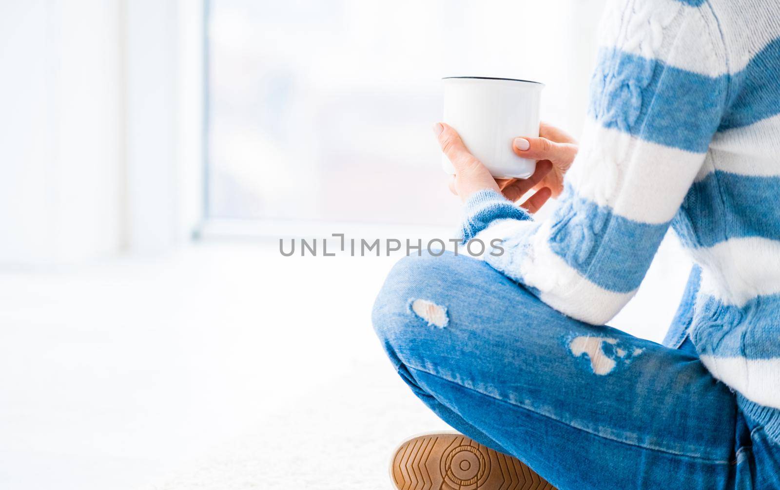 Girl relaxing near window with cup of tea indoors