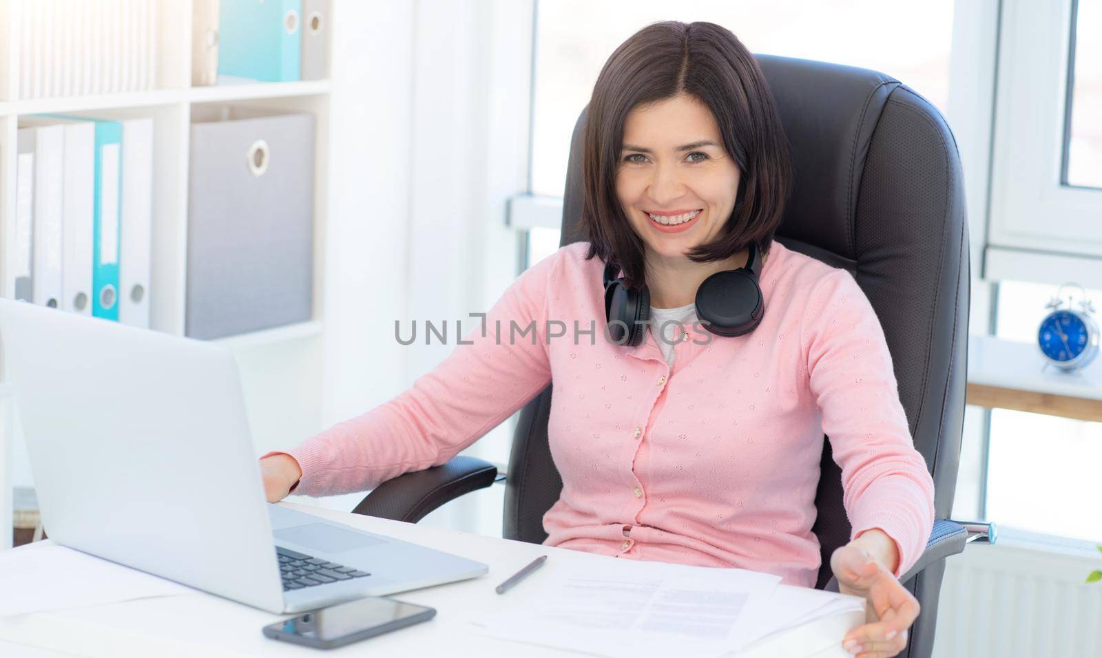 Cheerful business woman sitting in armchair at workplace