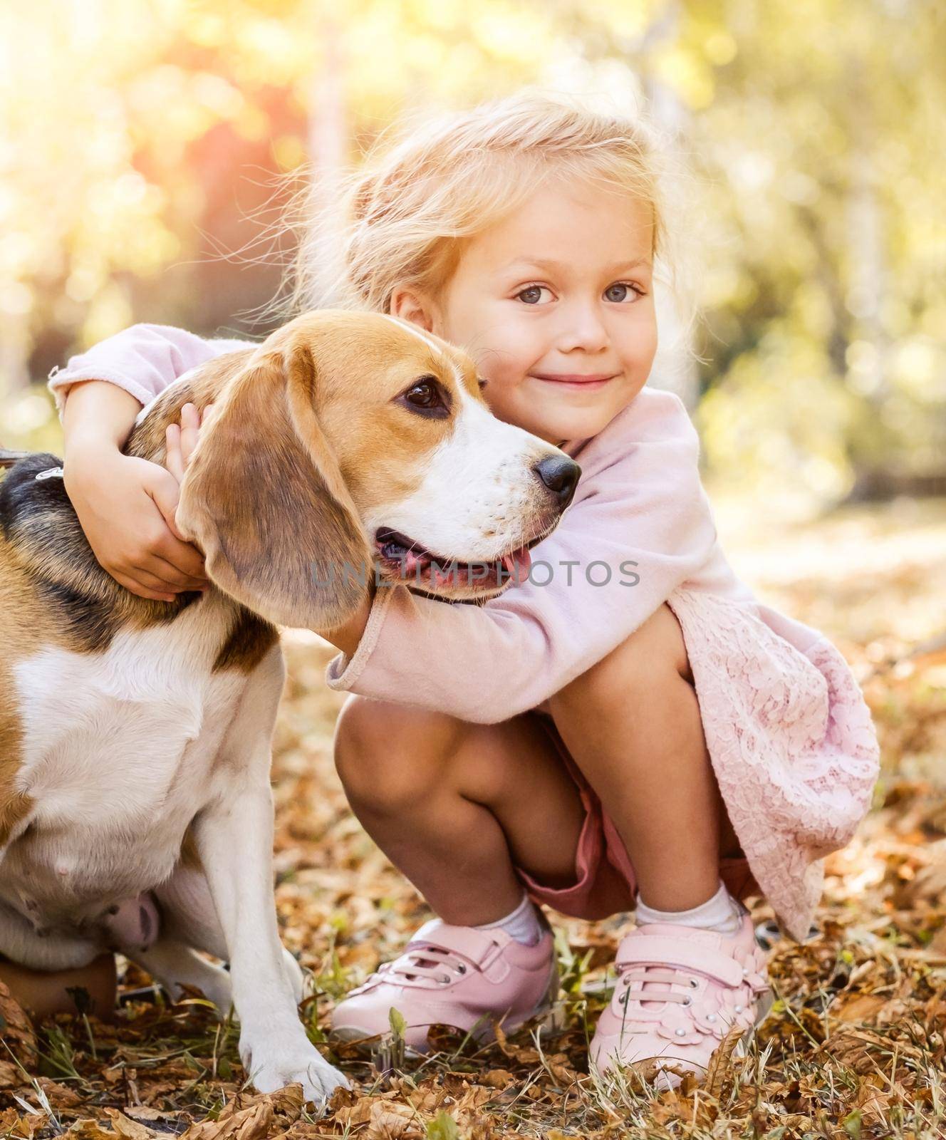 Smiling little girl hugging a beagle dog