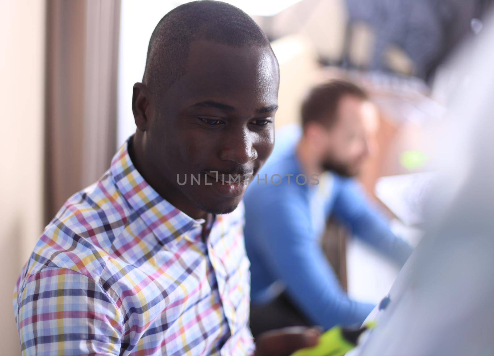 Portrait of a happy African American entrepreneur displaying computer in office.