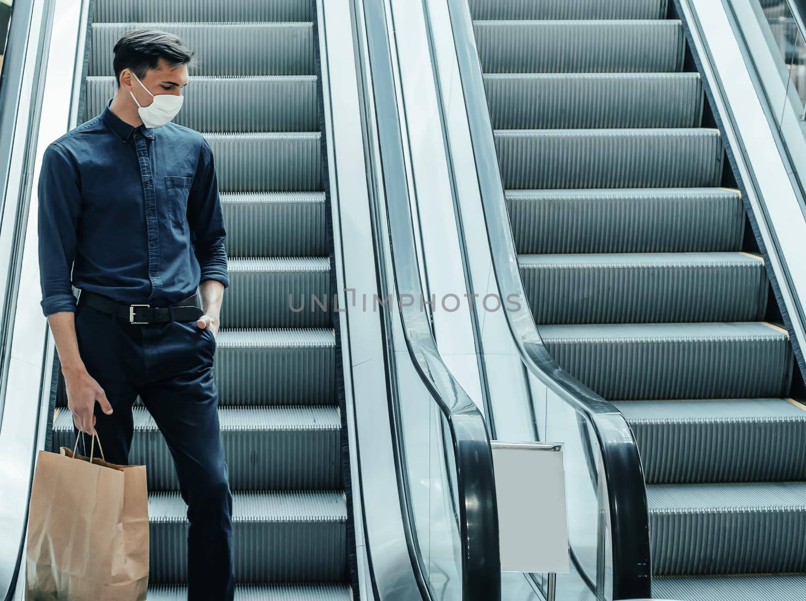 lone man in a protective mask standing on the escalator steps . photo with a copy-space