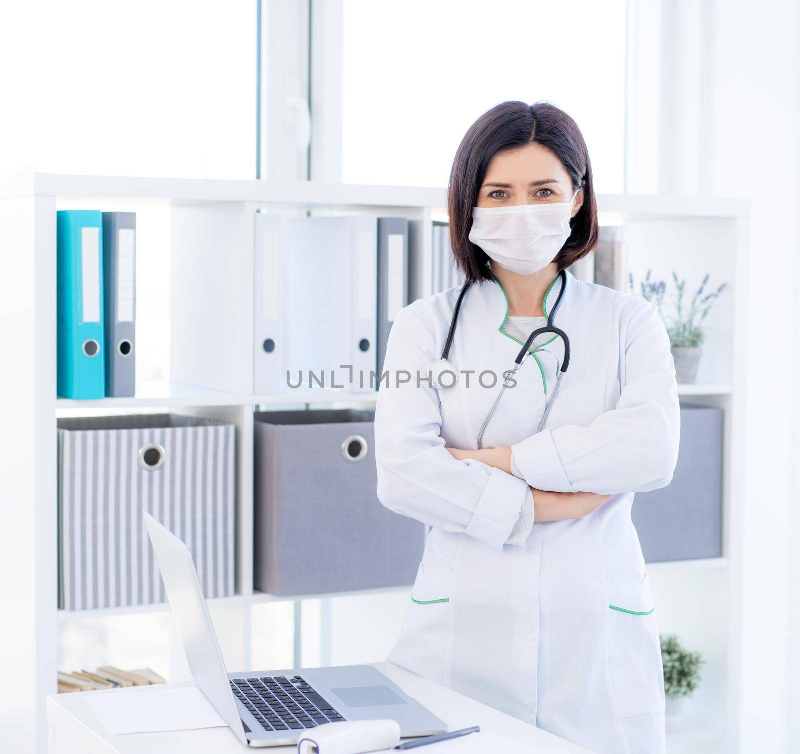 Nice doctor wearing face mask in light office