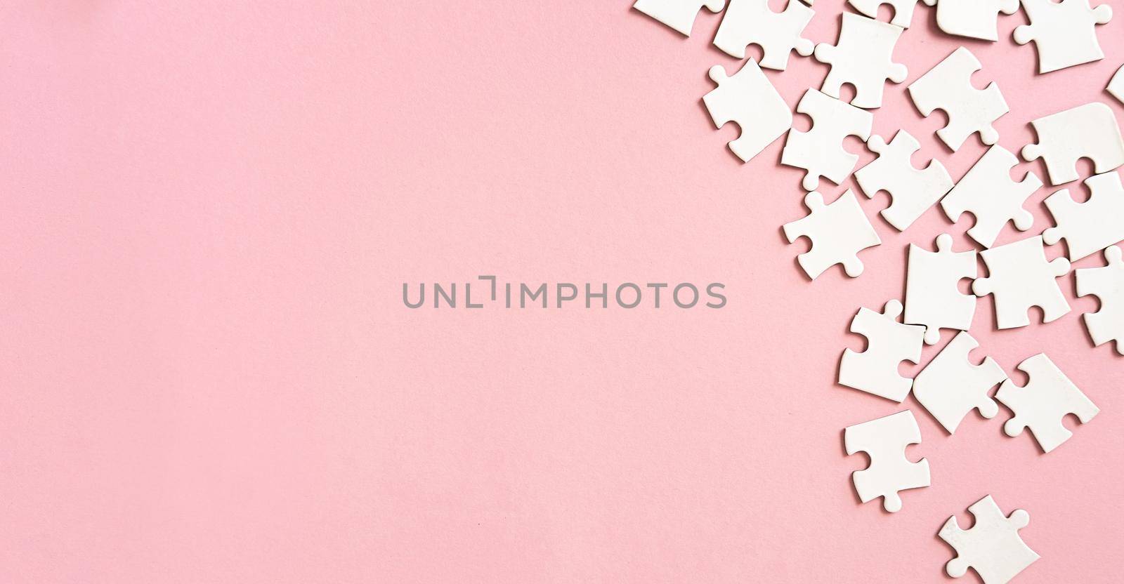 White jigsaw puzzle pieces in corner on pink background with copyspace