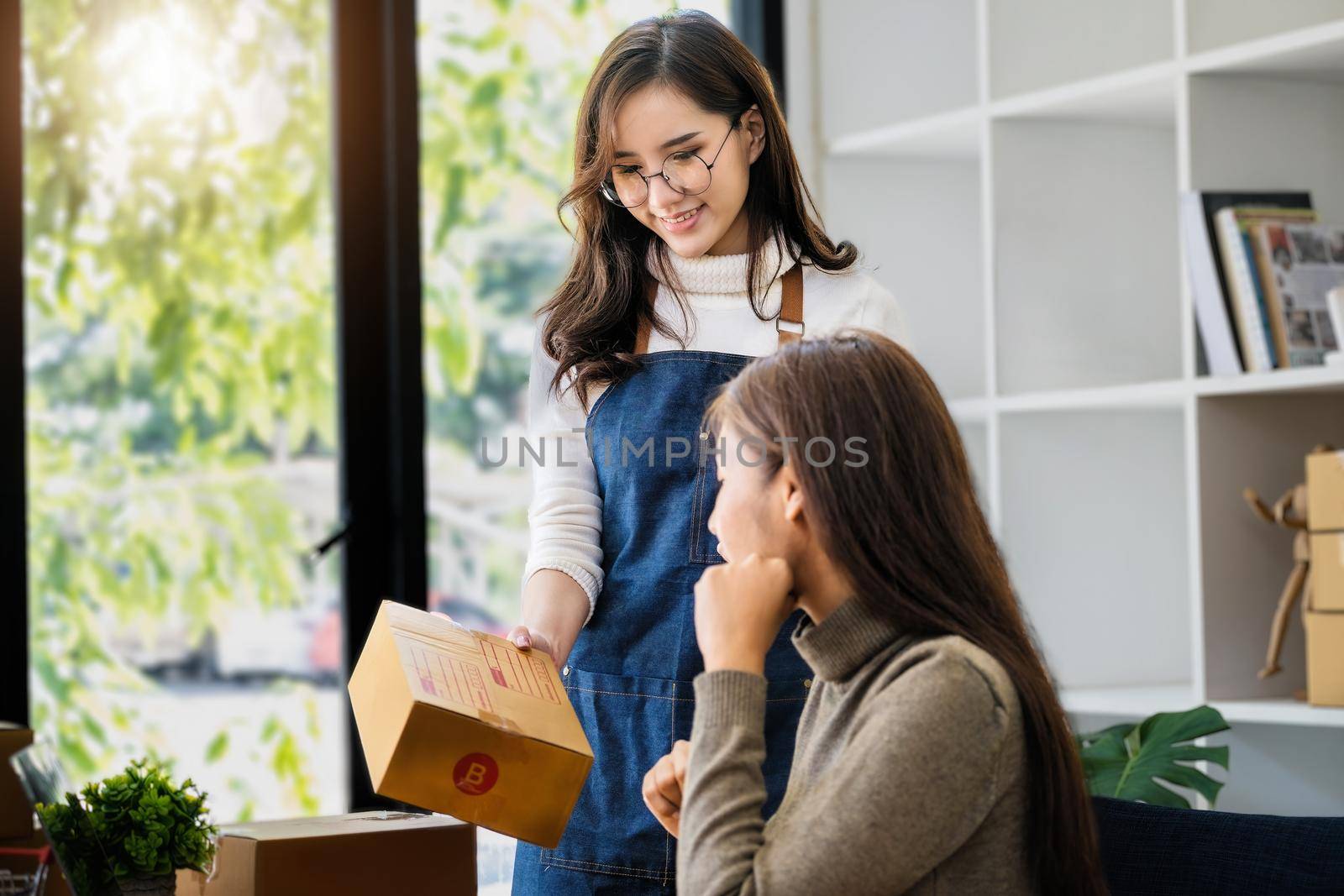 selling products online business owners Focusing on the face of a woman in white, she sends a box to a friend, writes down the delivery address for the customer and prepares it for postage