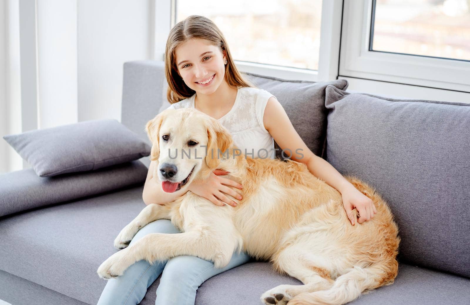 Smiling teenage girl with adorable dog in light room