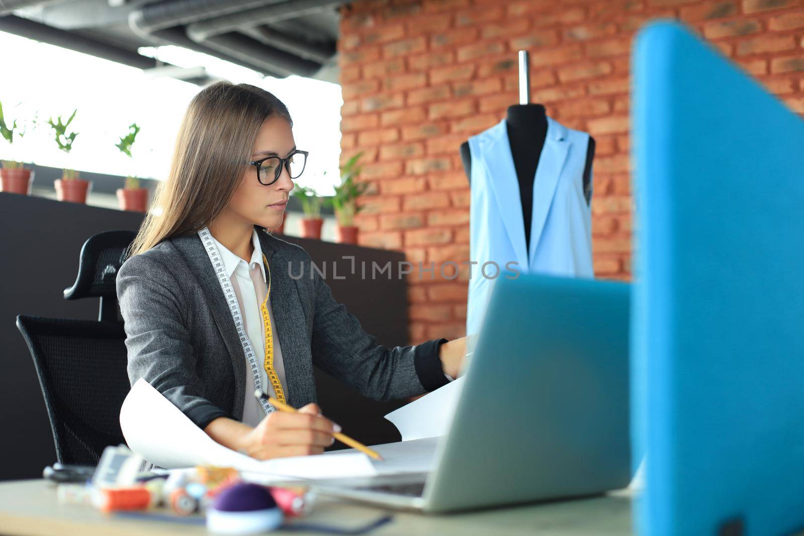 Beautiful young designer working on sketches while sitting in her studio