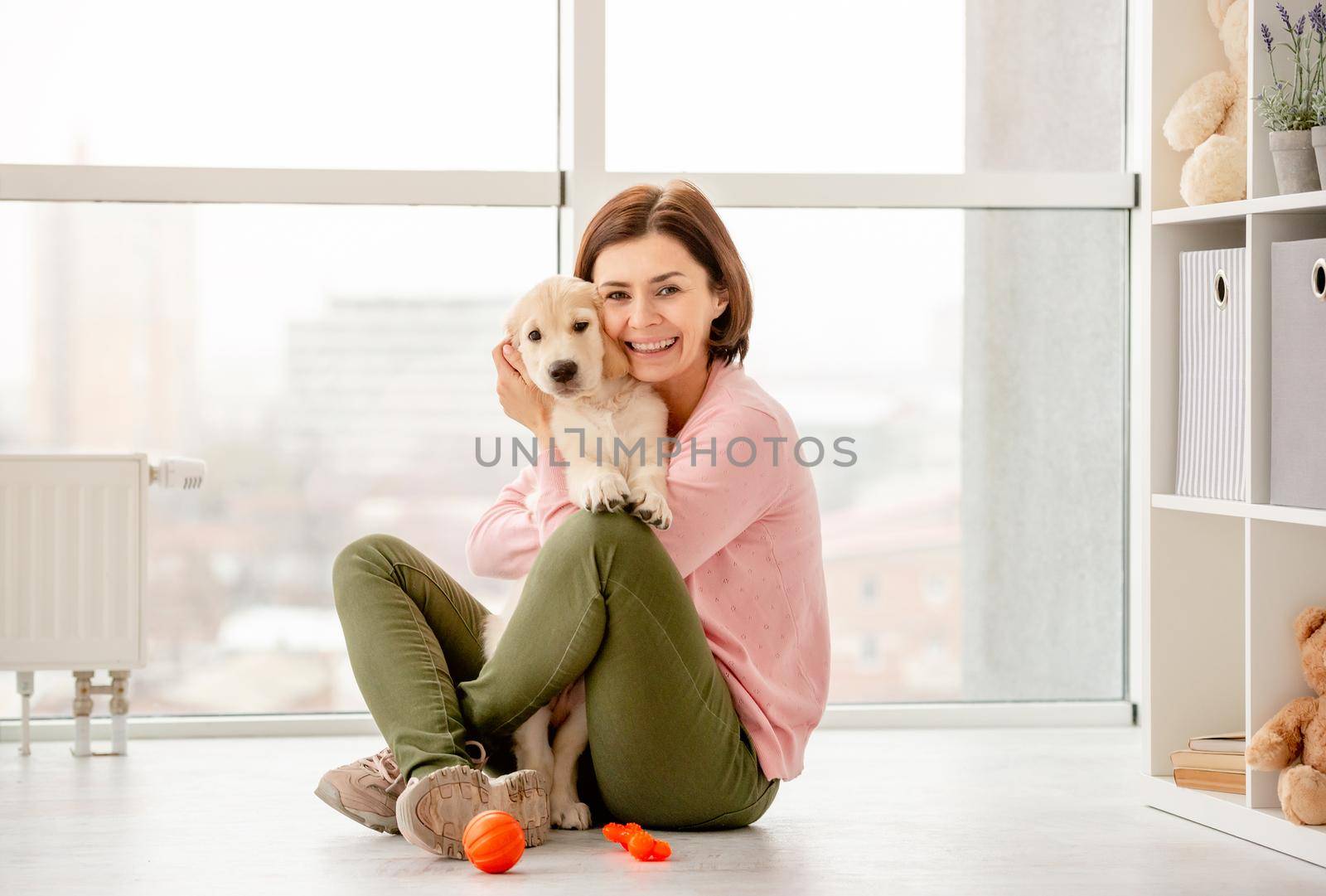 Happy woman cuddling cute puppy at home