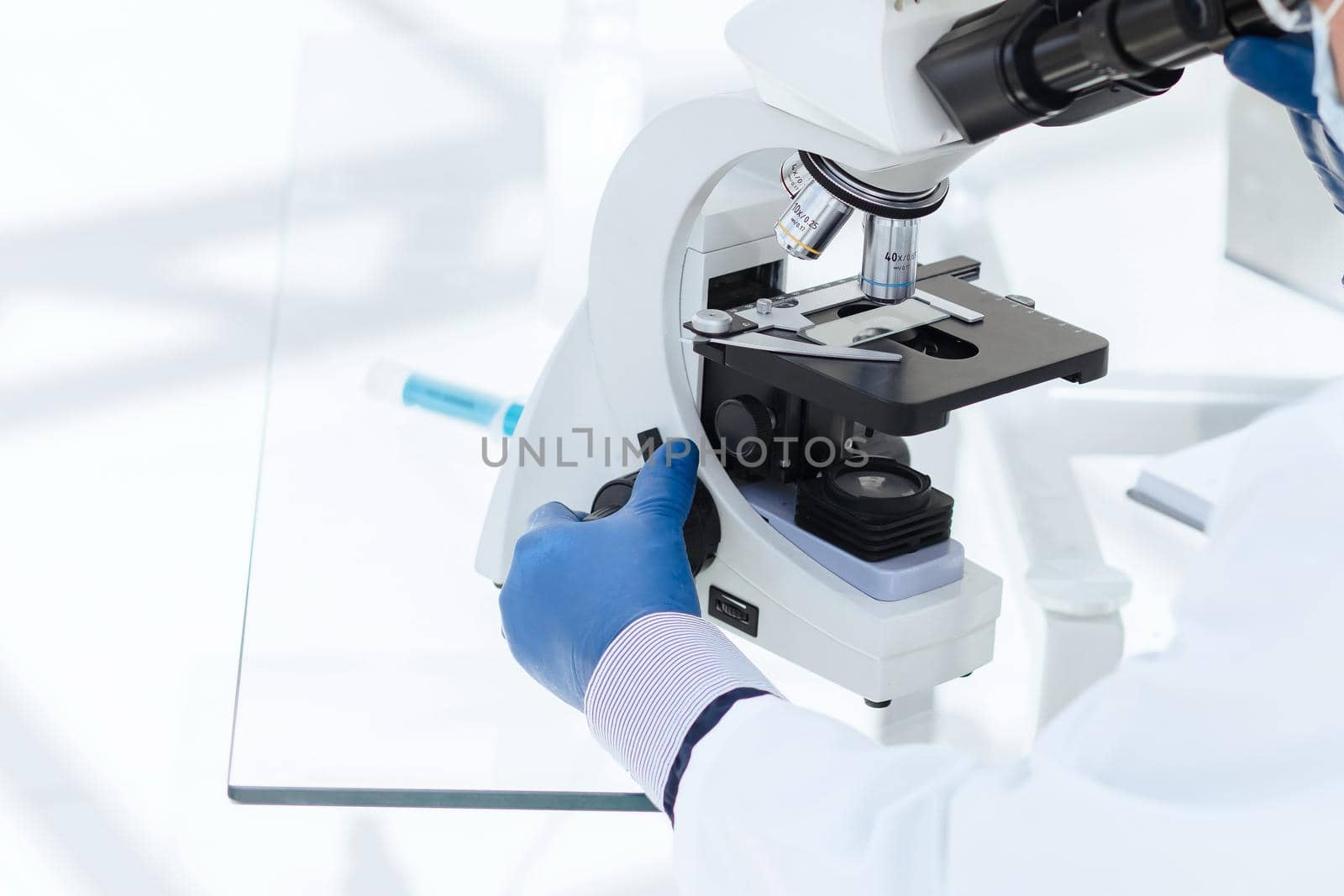 close up. scientist biologist in a protective mask looking through a microscope. science and health protection.