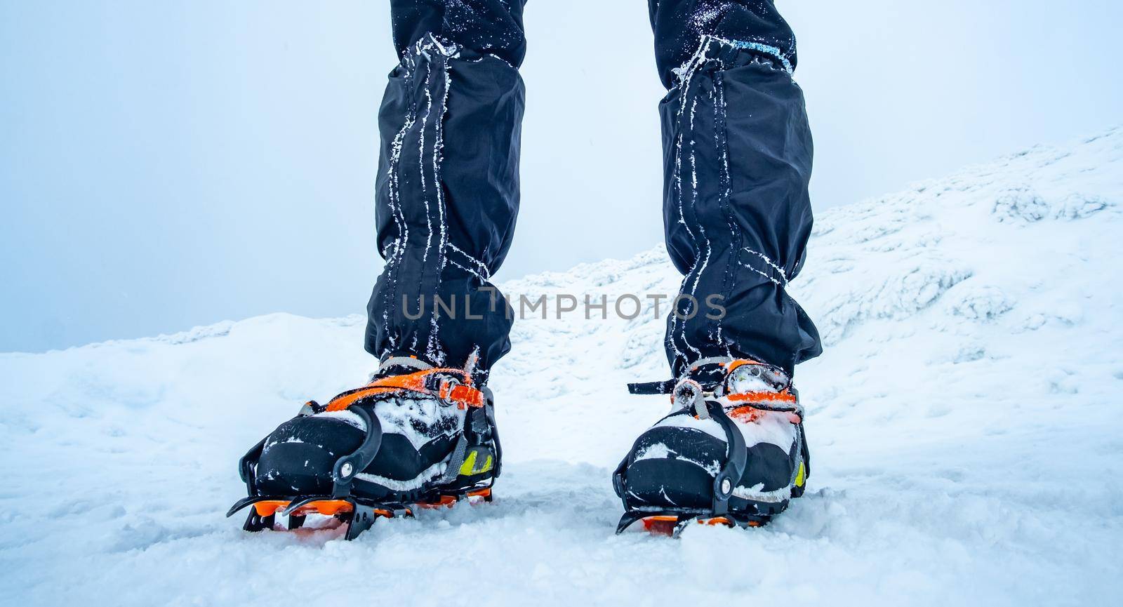Man wearing crampons on trekking boots on snow