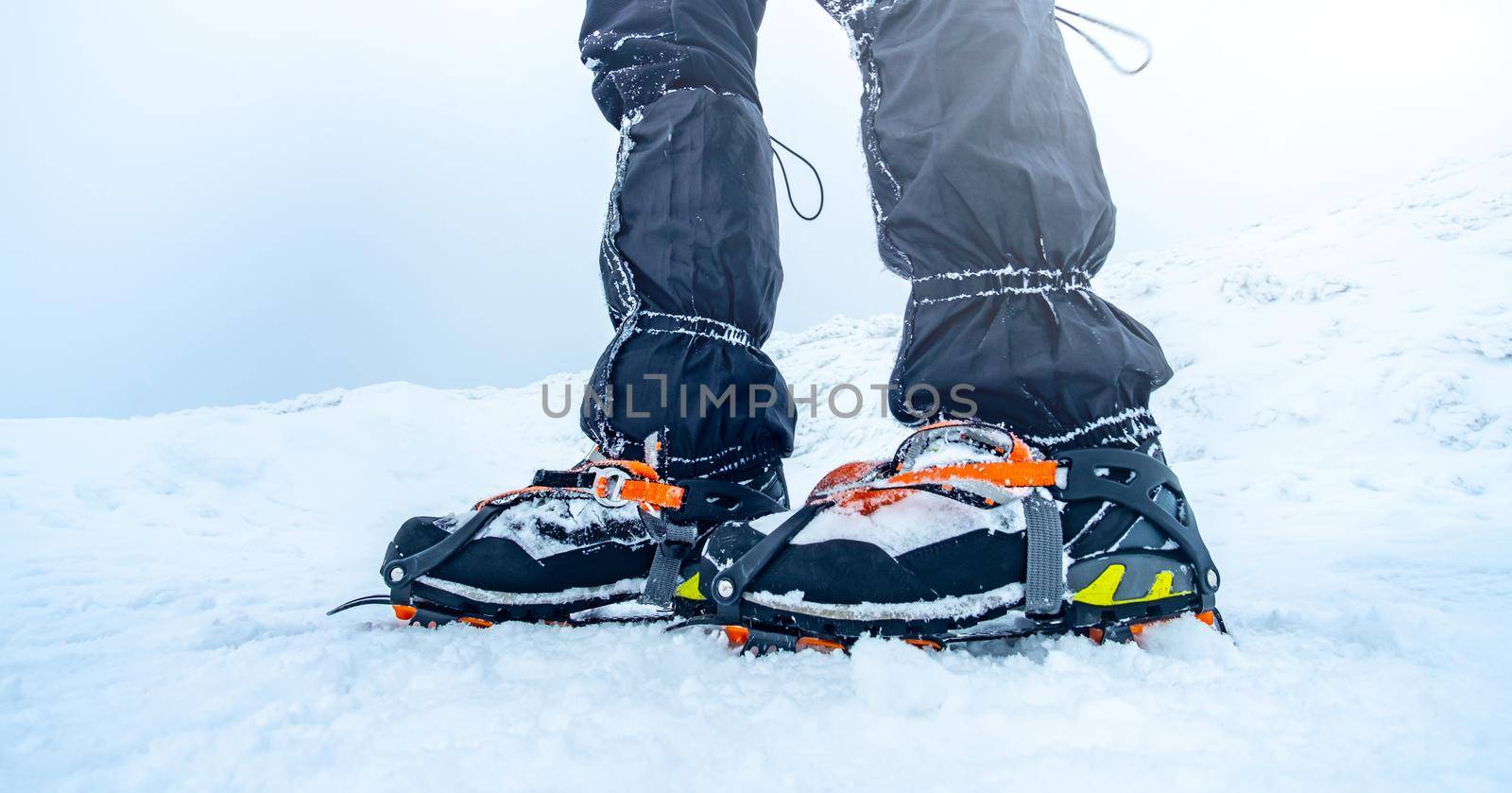 Man trekking snowy mountain using crampons for deep snow