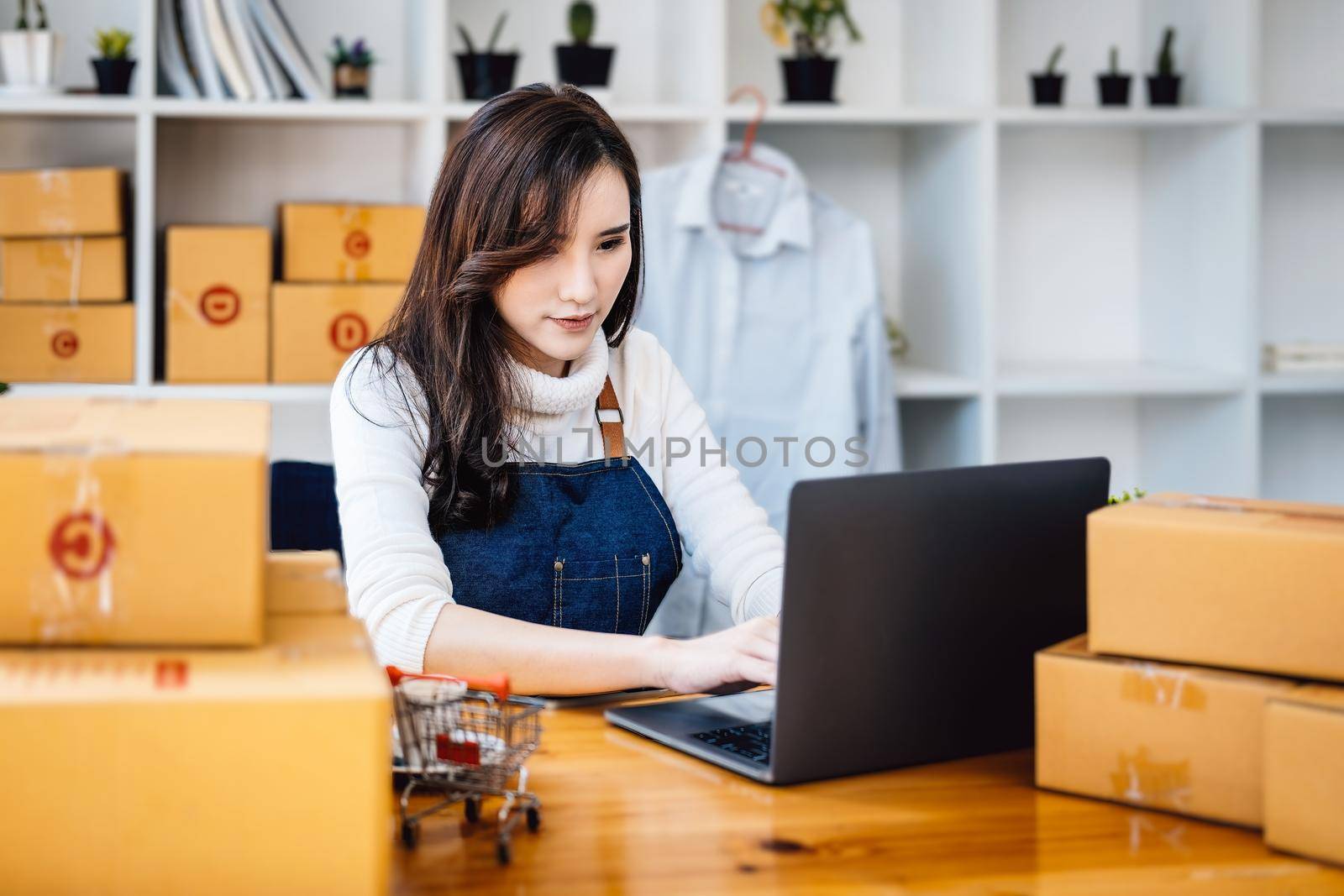 Work from home. happy women selling products online Start a small business owner by using laptop computer to calculate prices and prepare for postage. by Manastrong