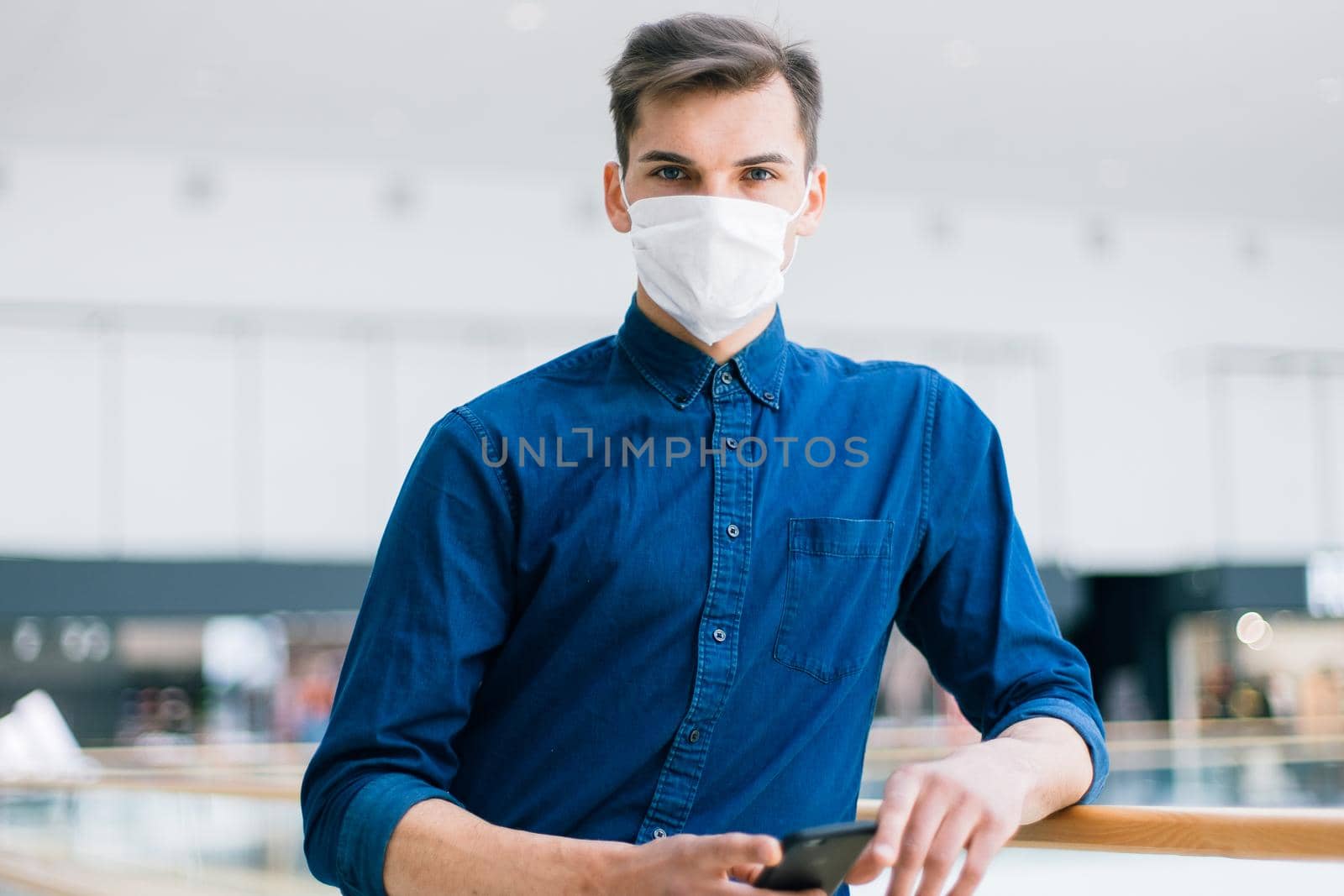 man in a protective mask with a smartphone standing on the street . photo with a copy of the space