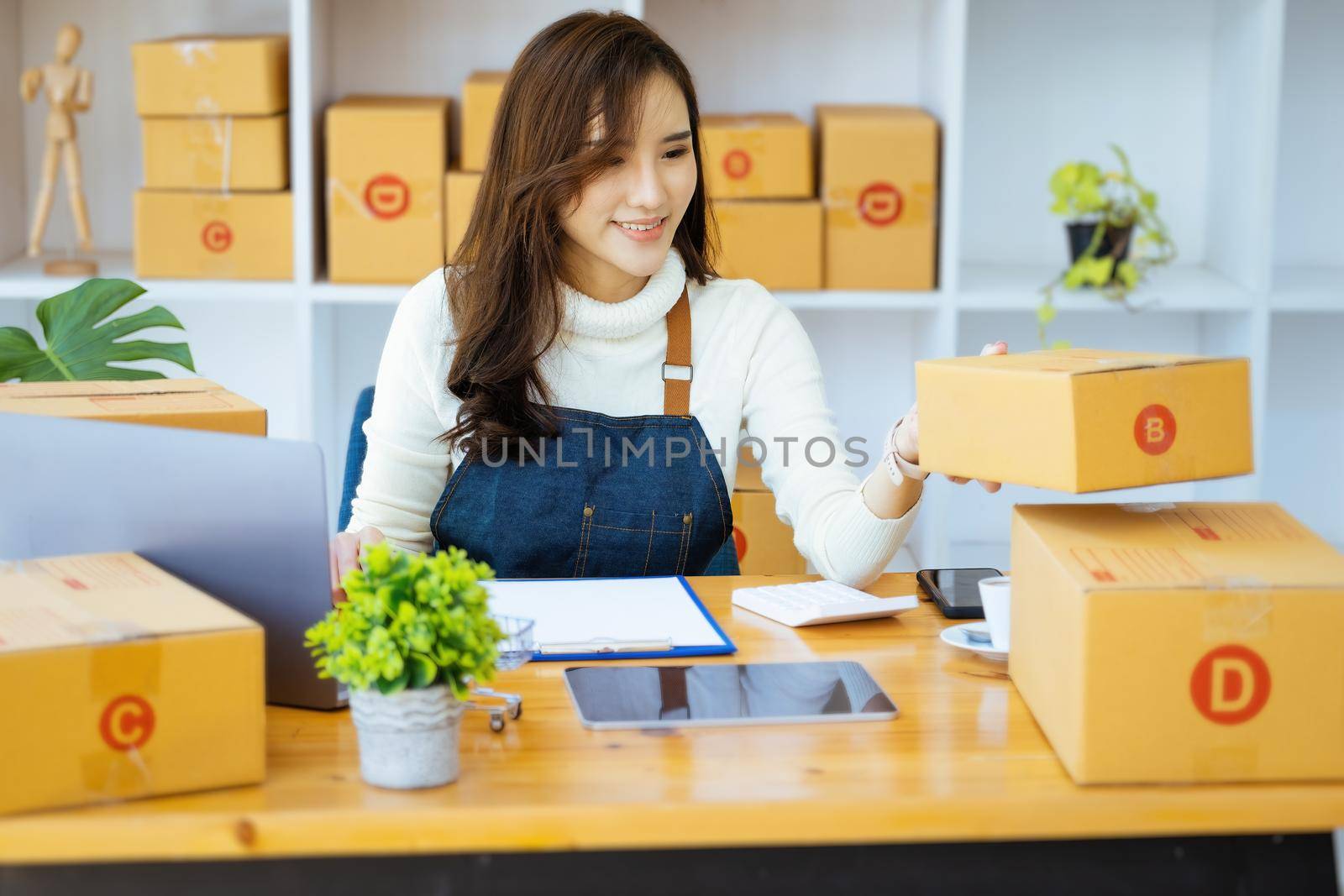 Work from home. happy women selling products online Startup small business owners are picking up parcel boxes to pack customer orders and prepare them for postage. by Manastrong